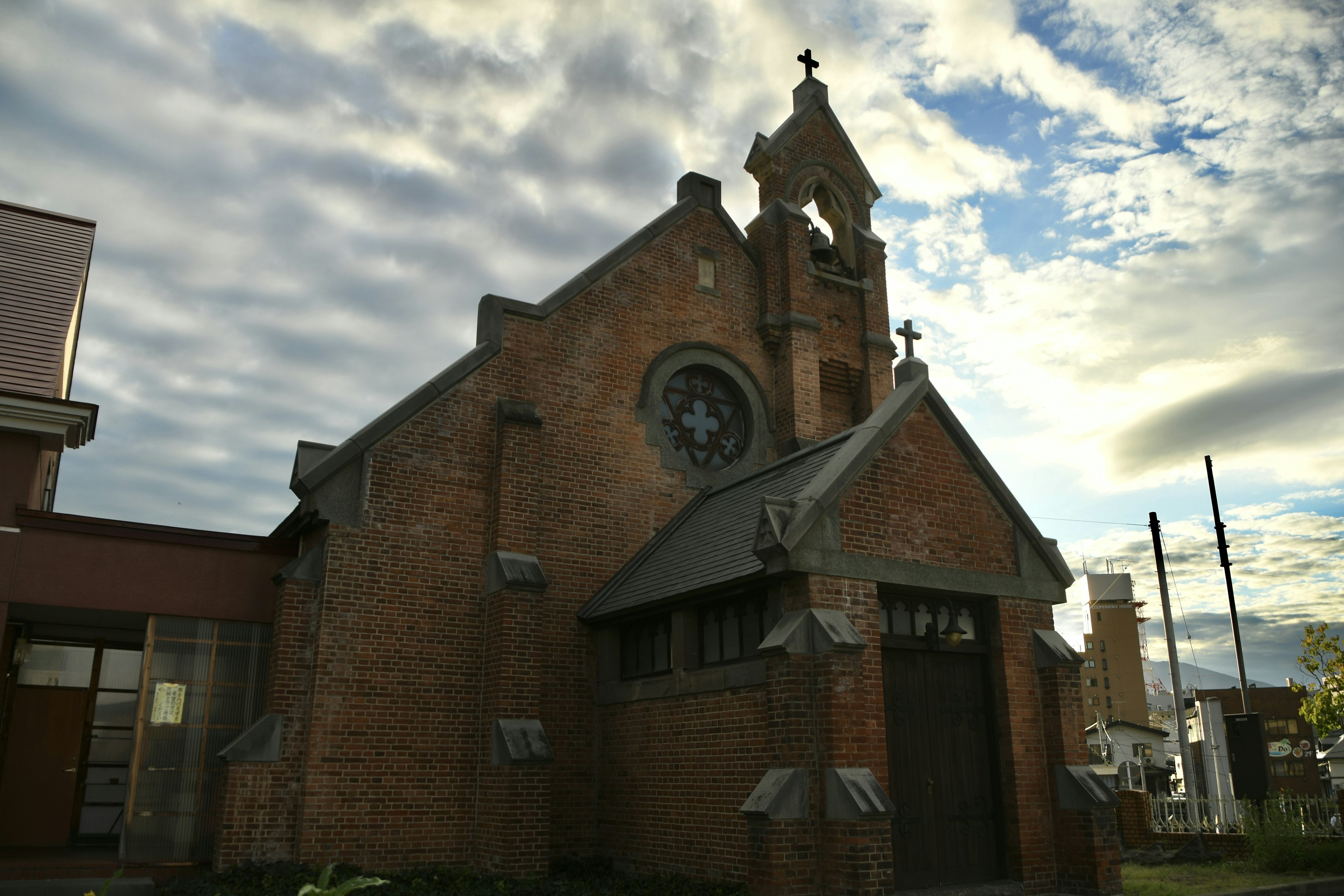 Iglesia de ladrillo con torre del reloj y cielo nublado