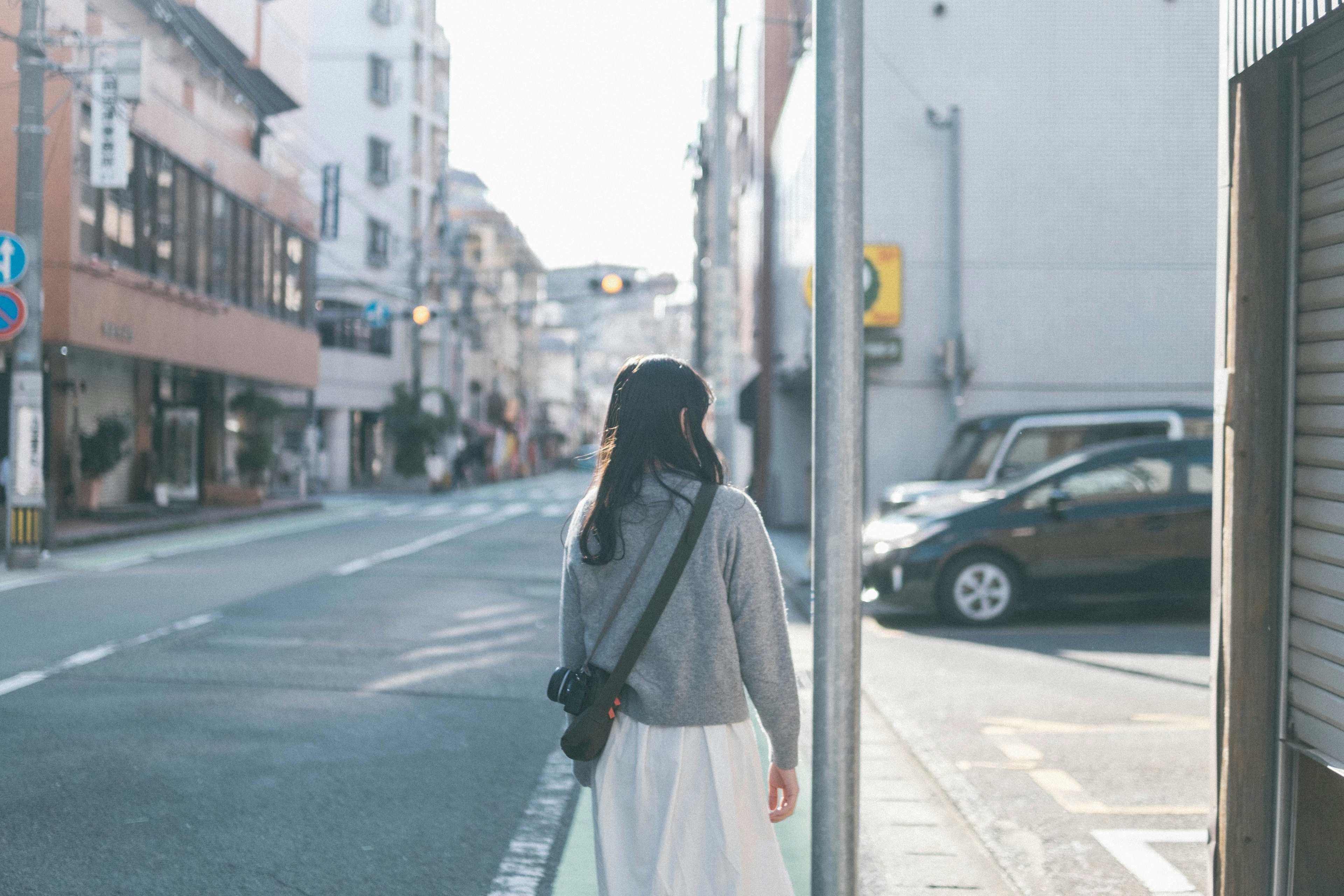 A woman walking on a quiet street with buildings in the background