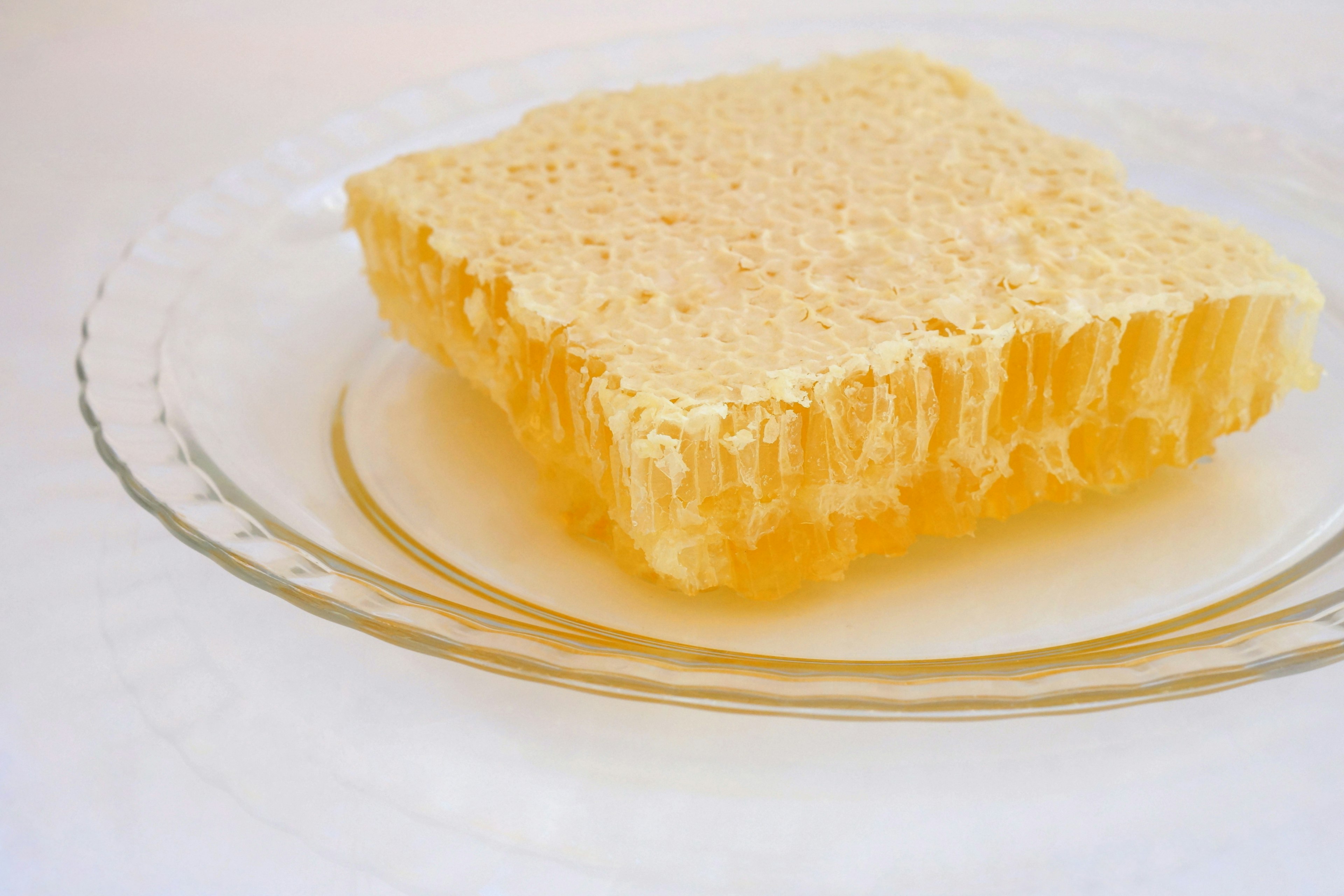 Une structure de miel en nid d'abeille translucide placée sur une assiette transparente