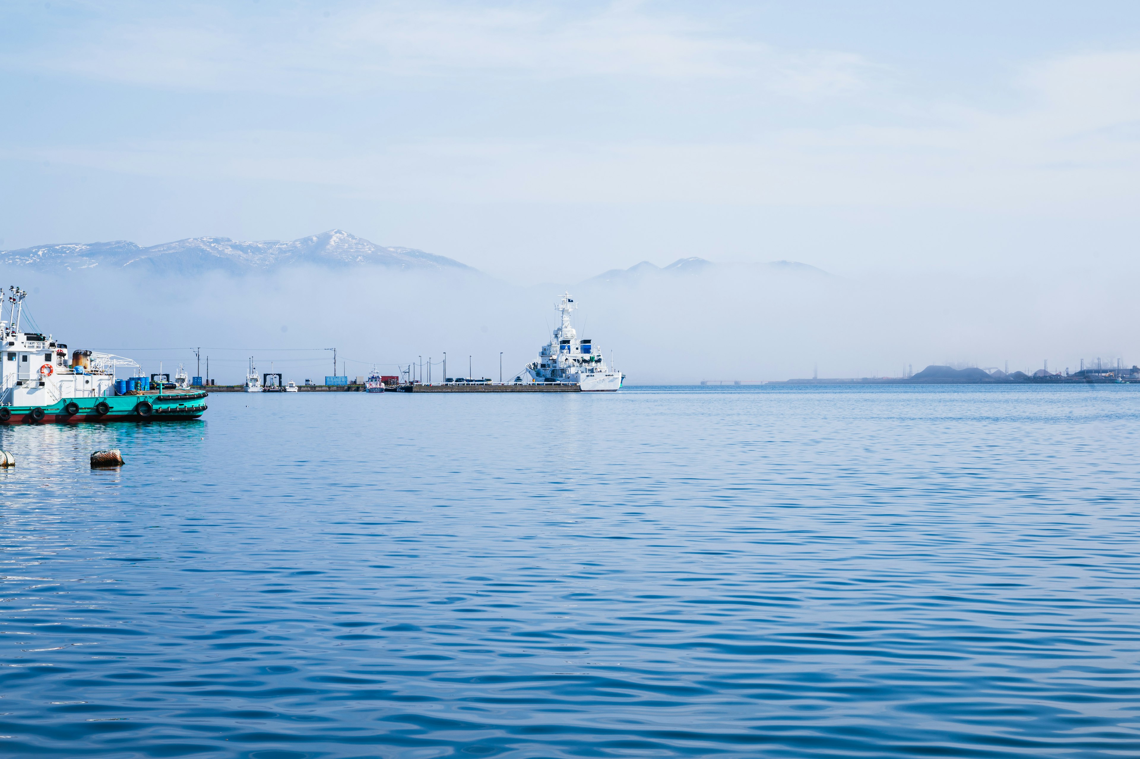 Surface d'eau calme avec des bateaux et des montagnes au loin