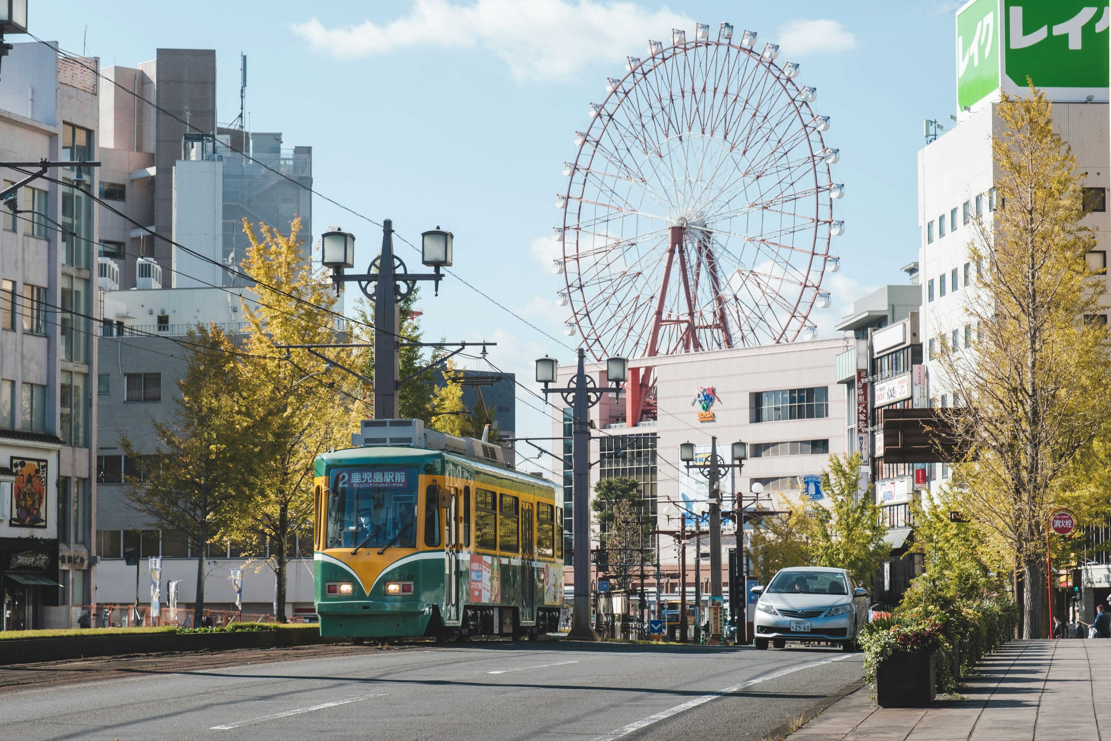 街の風景にある路面電車と観覧車のある風景