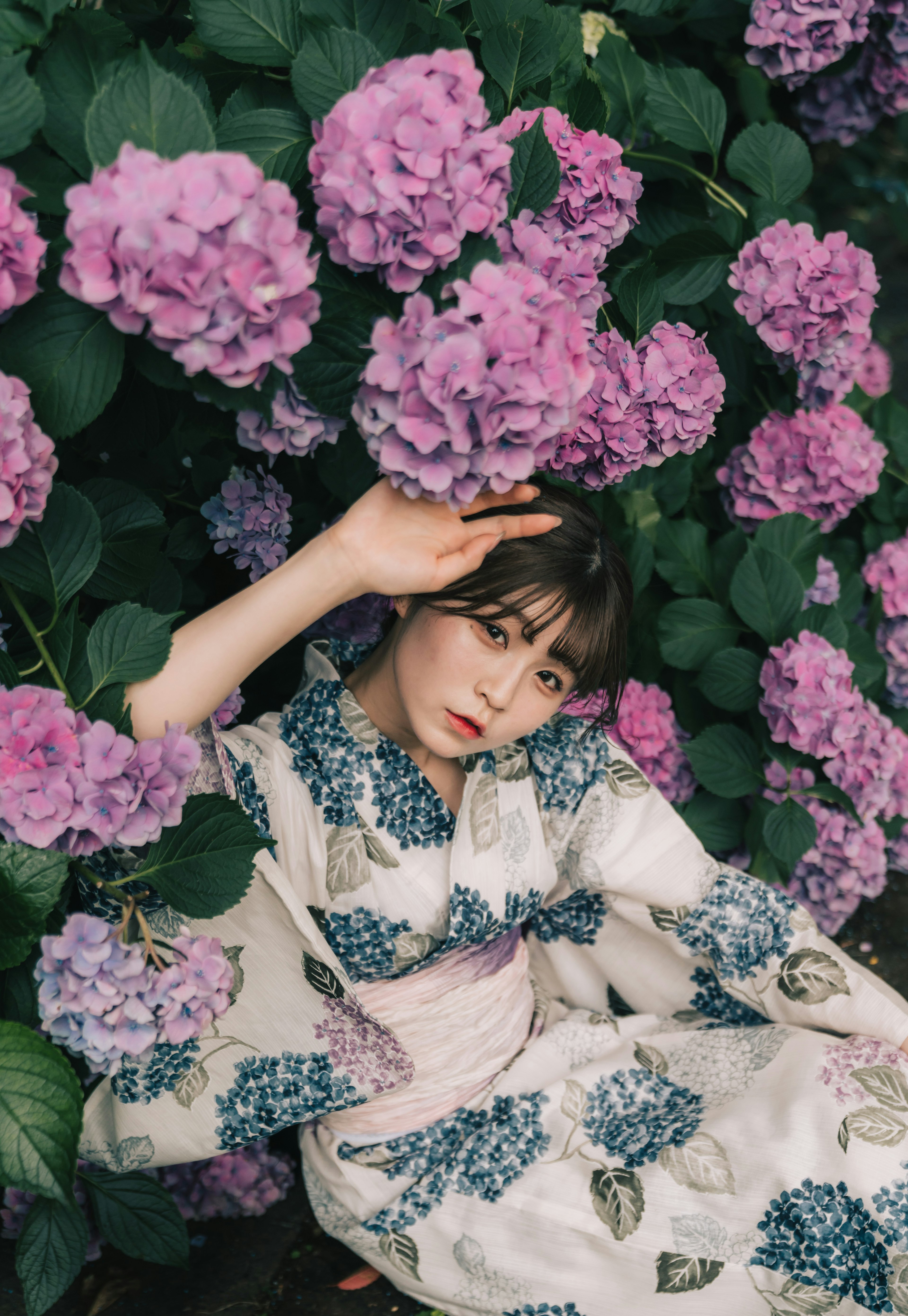 Una donna in kimono circondata da ortensie in fiore