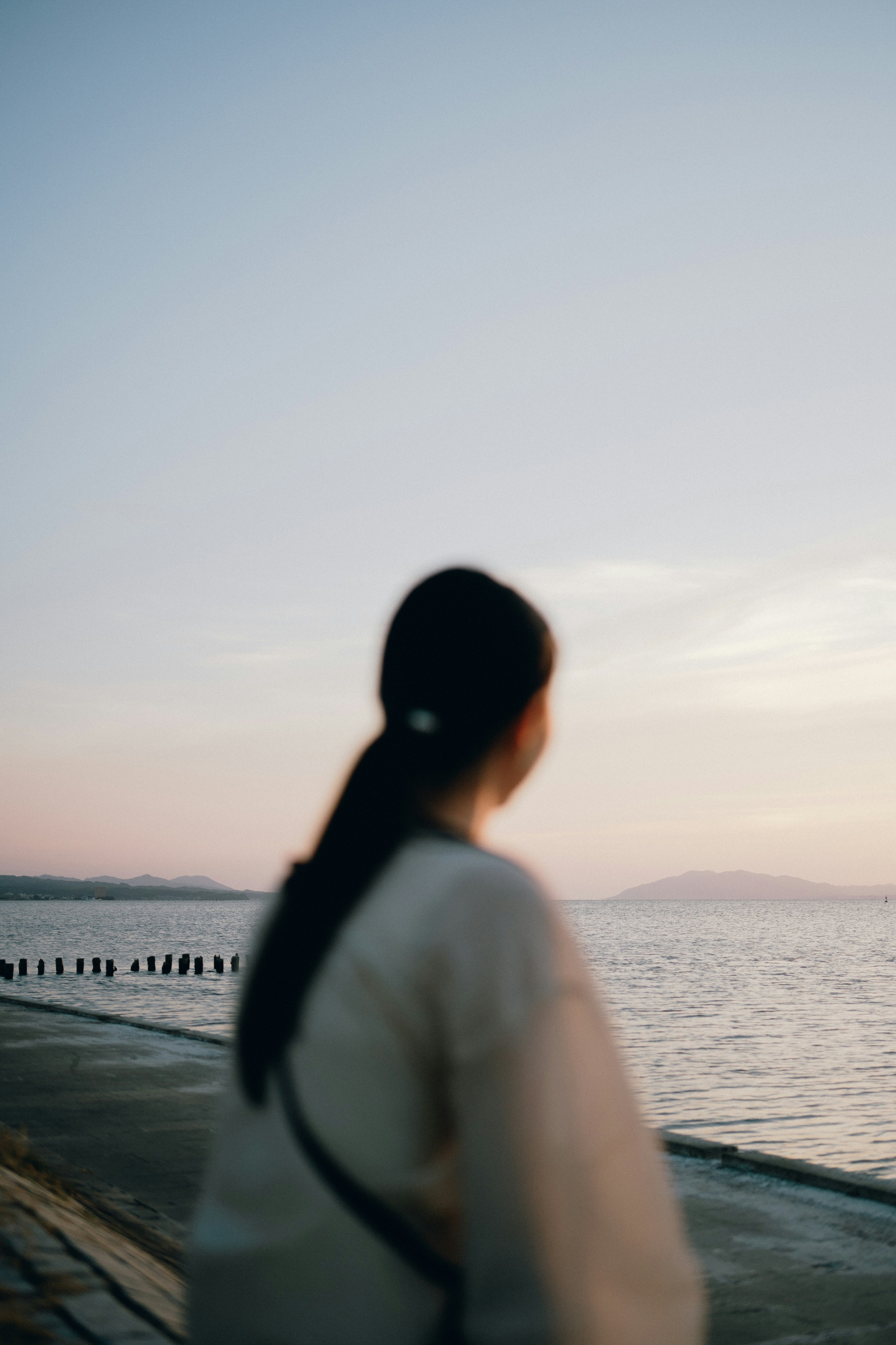 Silhouette of a woman gazing at the seaside with a calm sunset