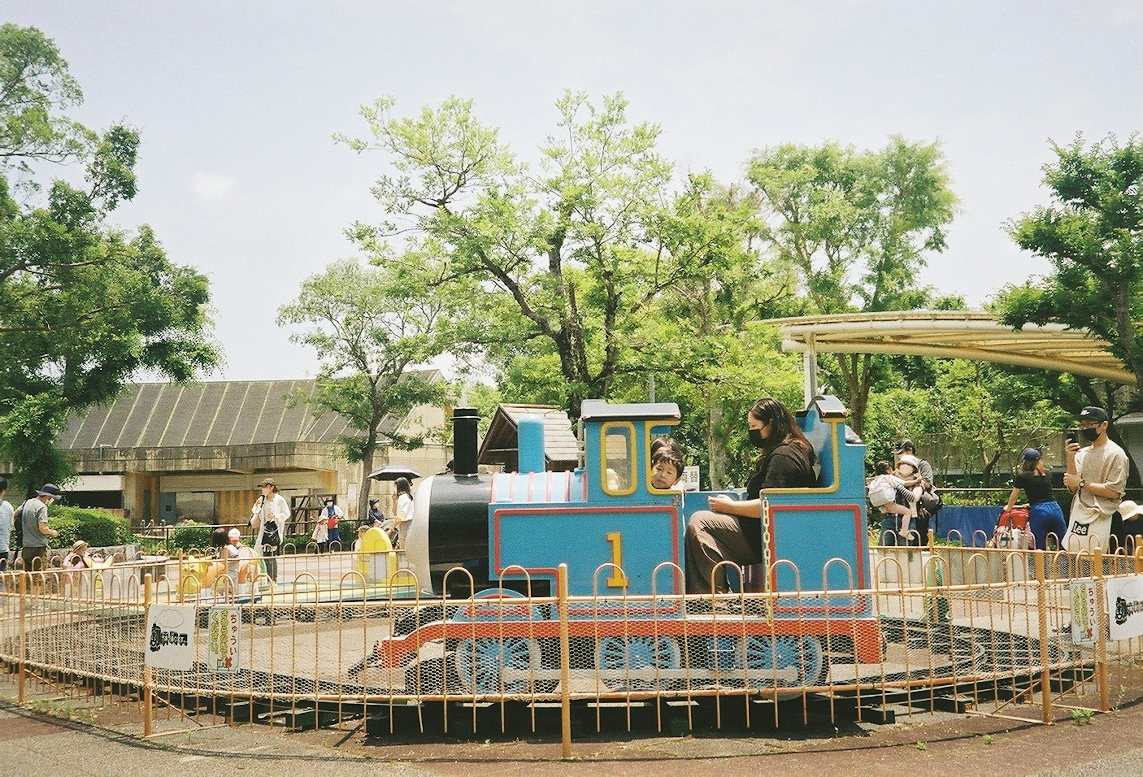 孩子们在公园里玩蓝色迷你火车