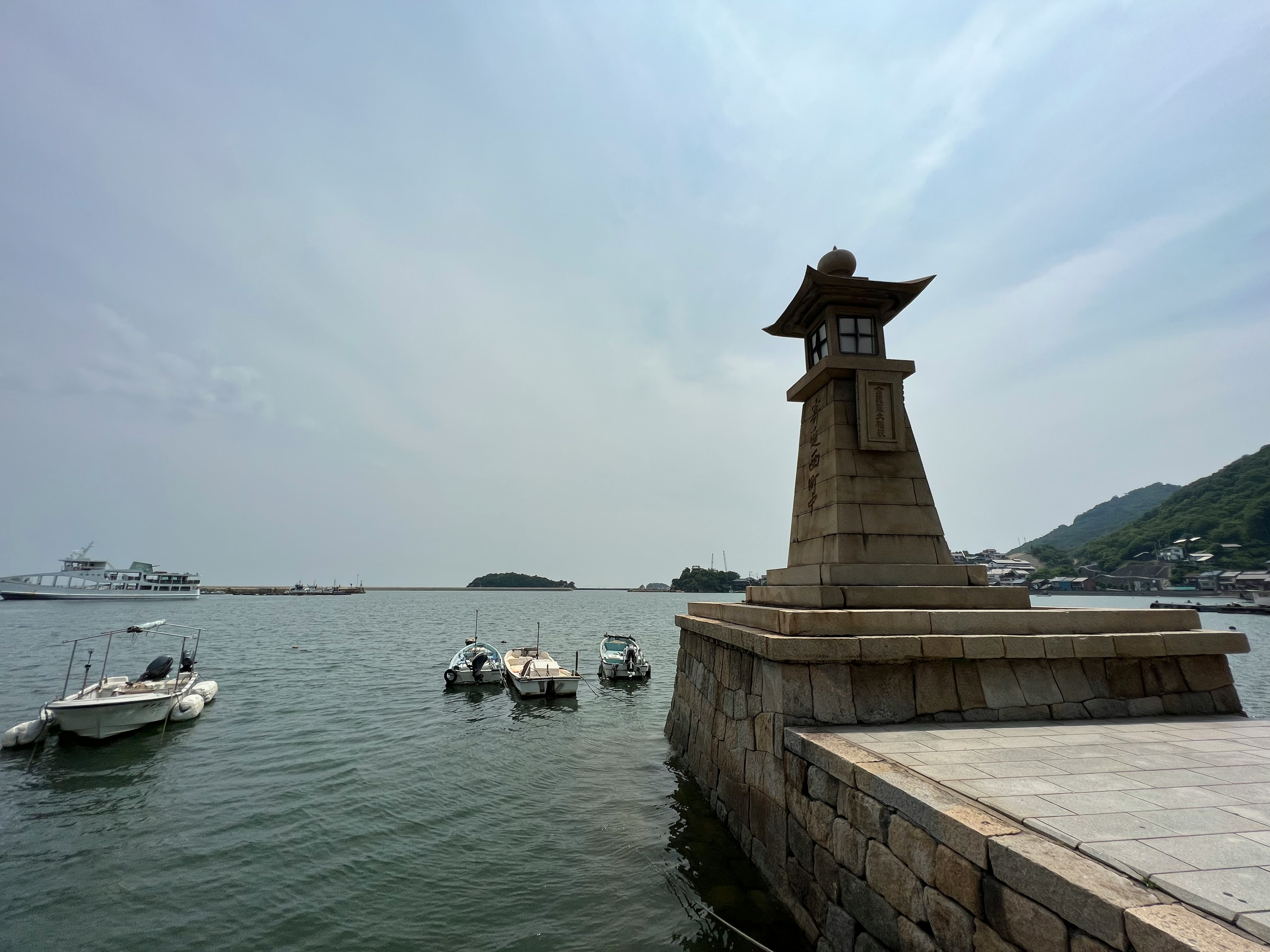 海に面した灯台と小型ボートが浮かぶ風景