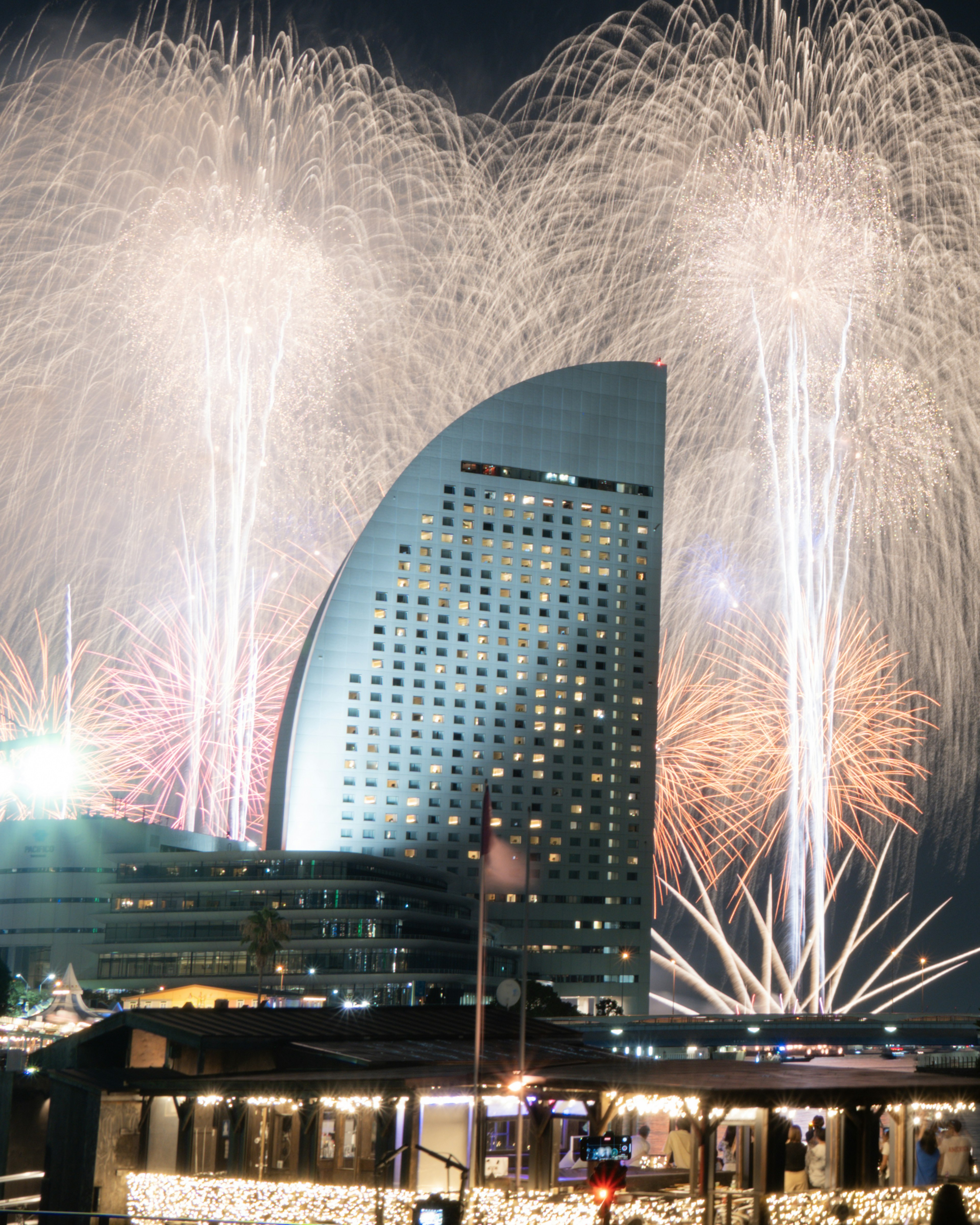 夜空に花火が打ち上げられる横浜のランドマークビル