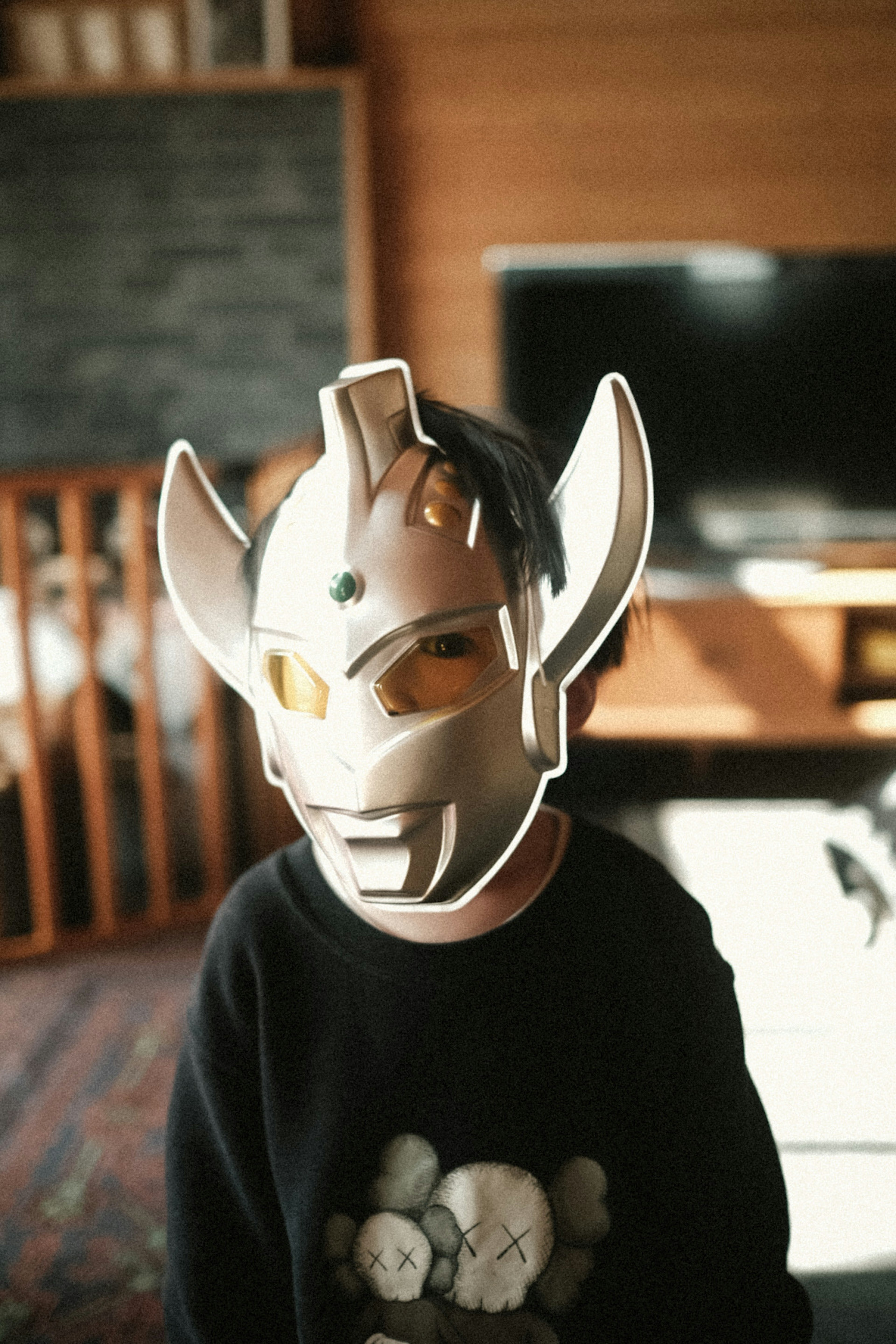 Child wearing an Ultraman mask in an indoor setting