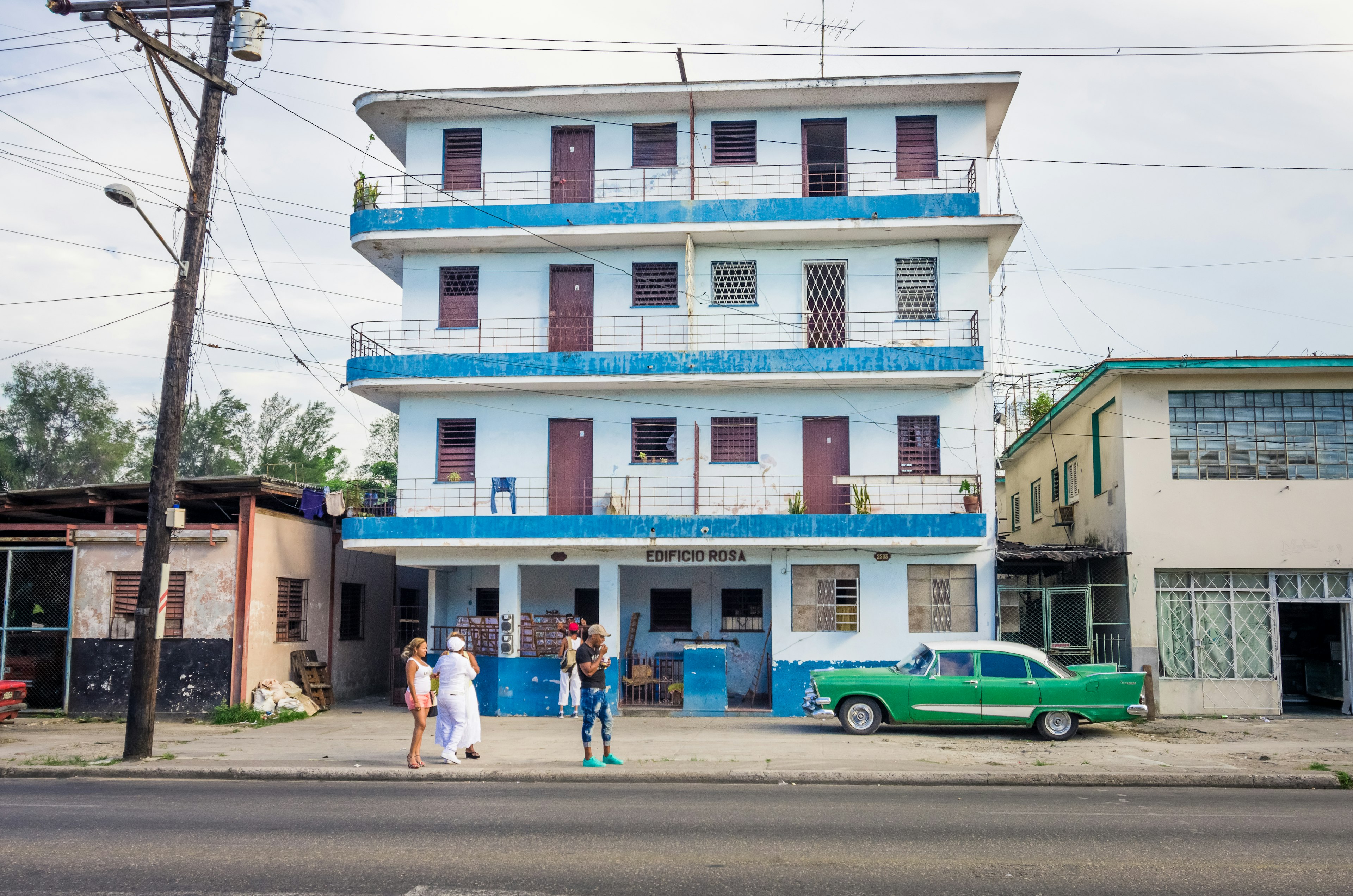 Scène de rue avec un bâtiment bleu et blanc et une voiture verte