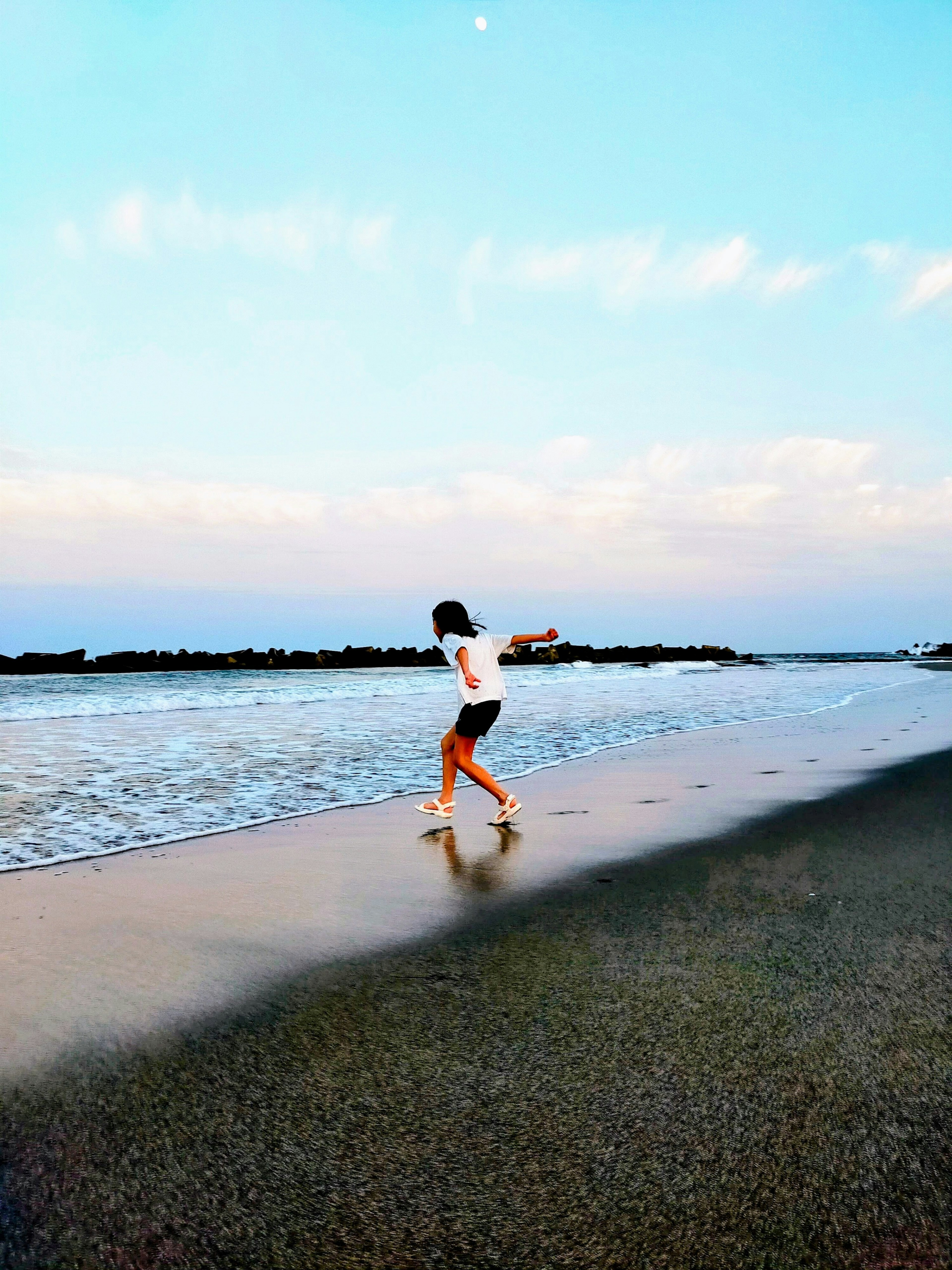 Kind spielt am Strand mit sanften Wellen