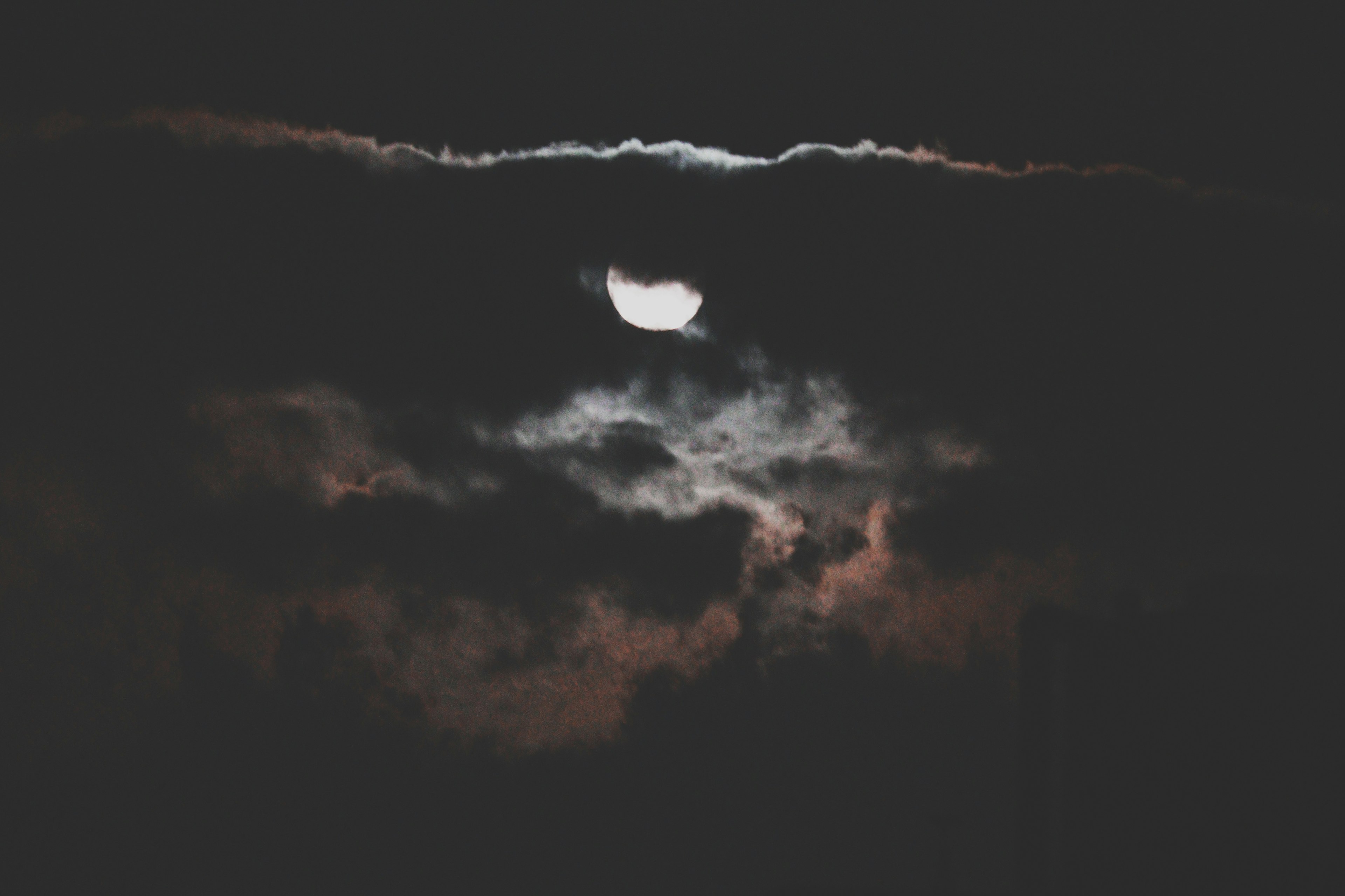 Full moon partially obscured by dark clouds