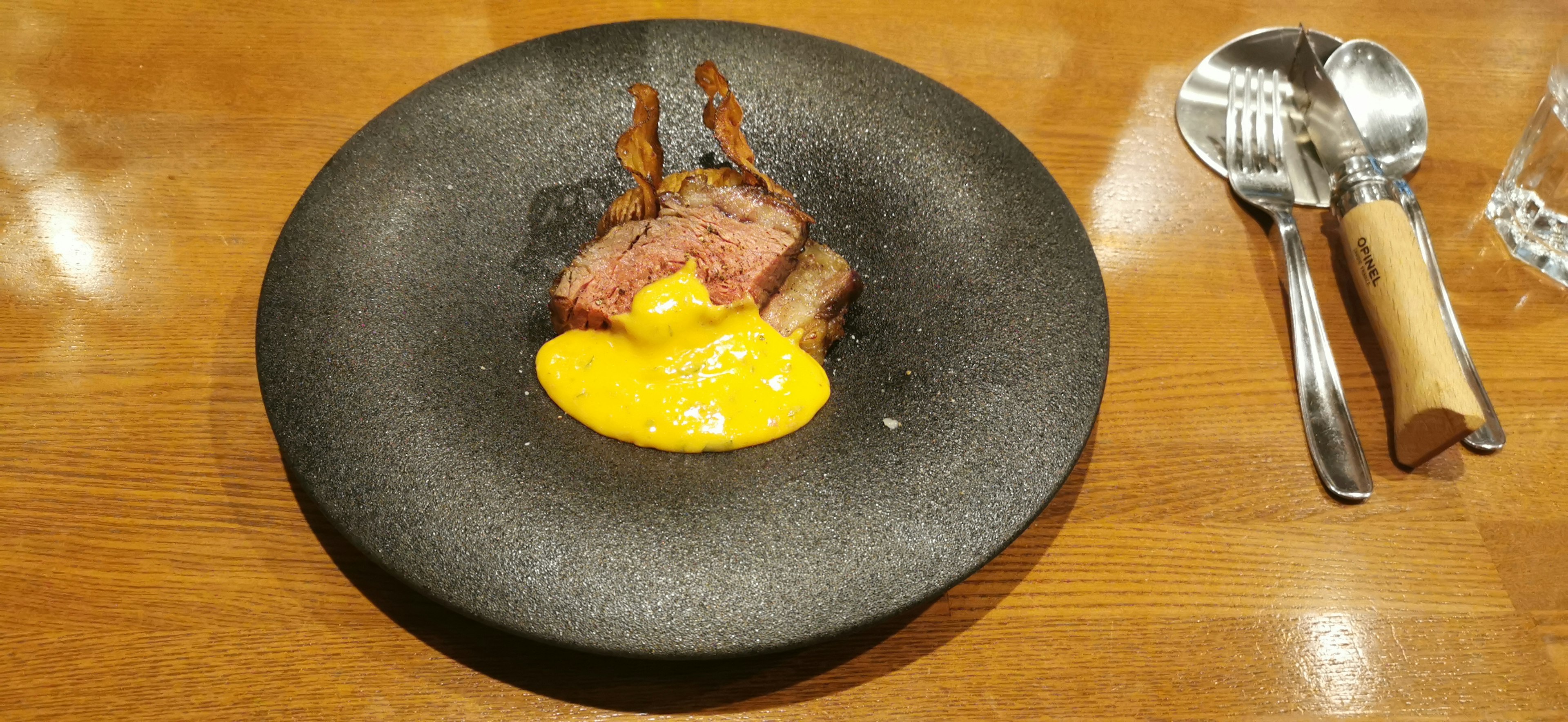 Dish featuring meat and egg yolk on a black plate