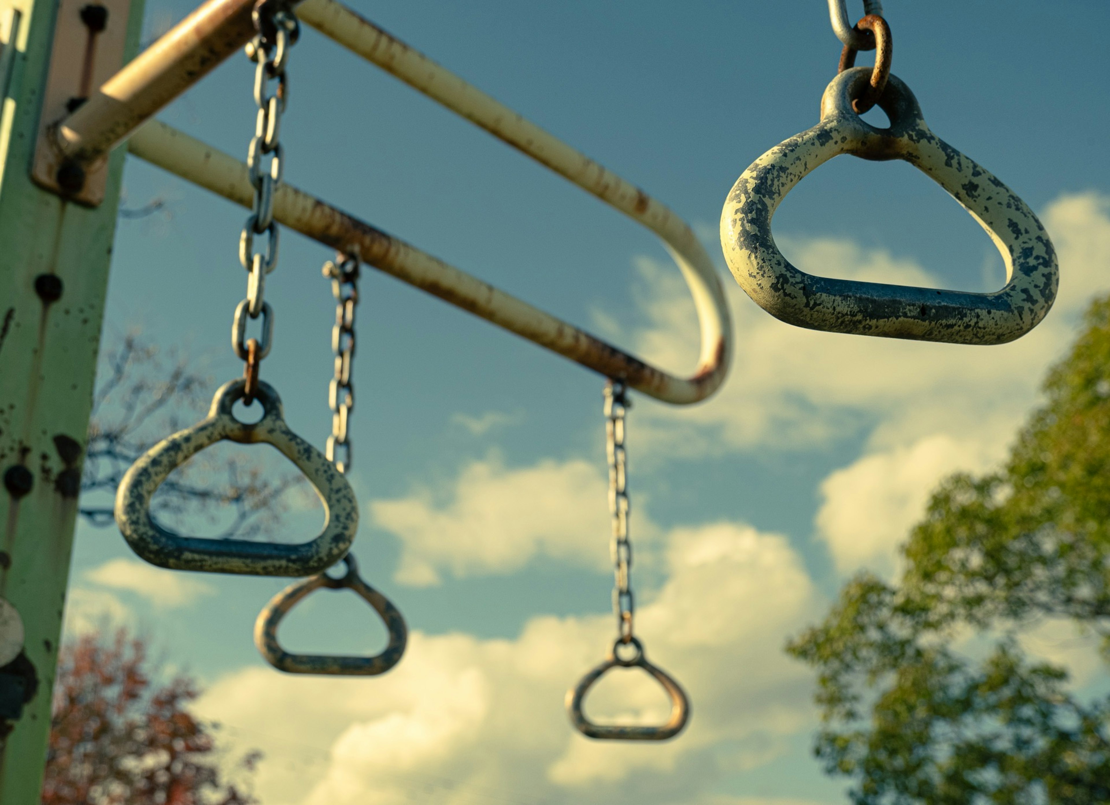 Swings hanging from chains against a blue sky with fluffy clouds