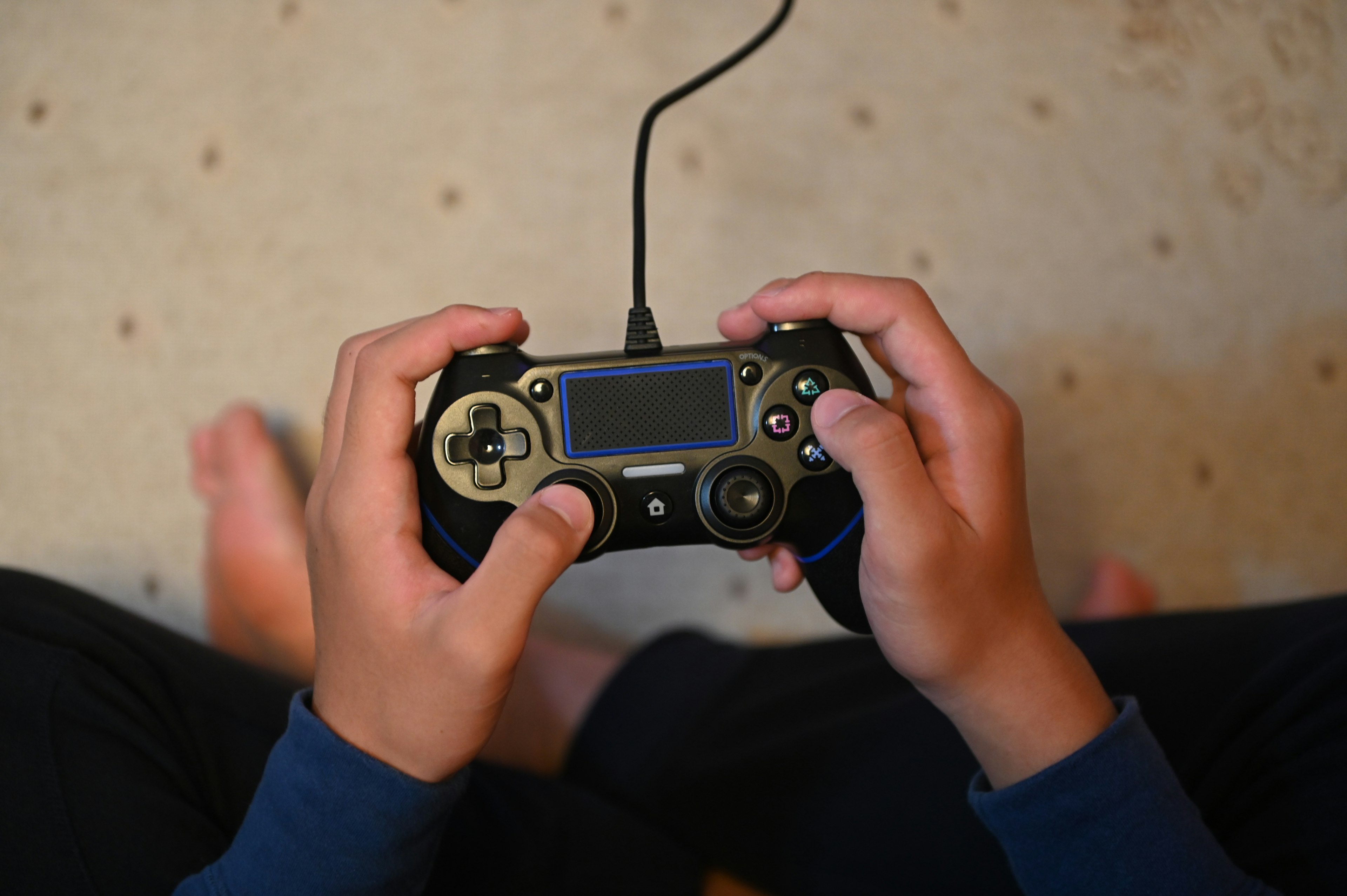 Mani di un bambino che tengono un controller di gioco con piedi nudi visibili