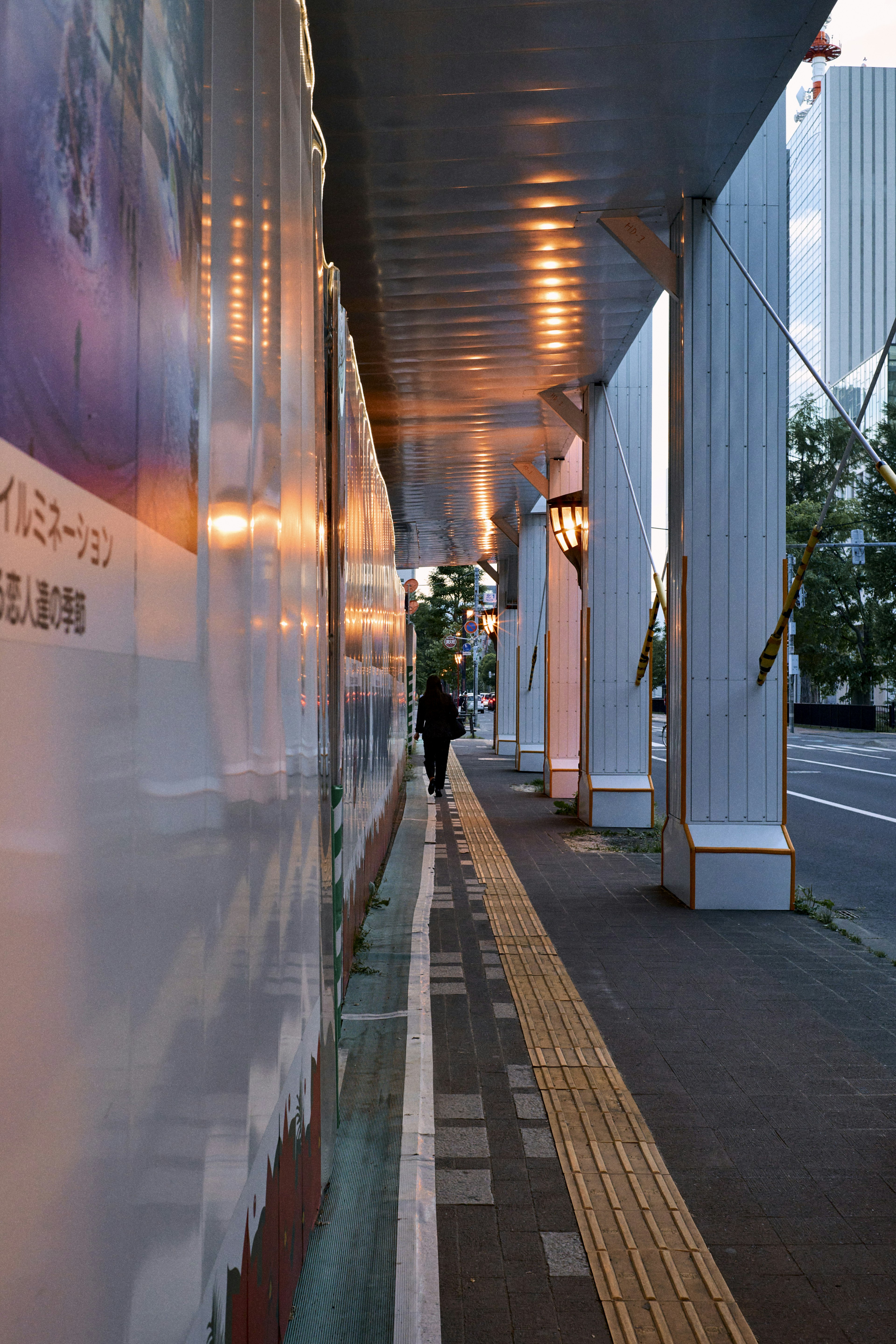 都市の歩道と看板が映る夕暮れの風景