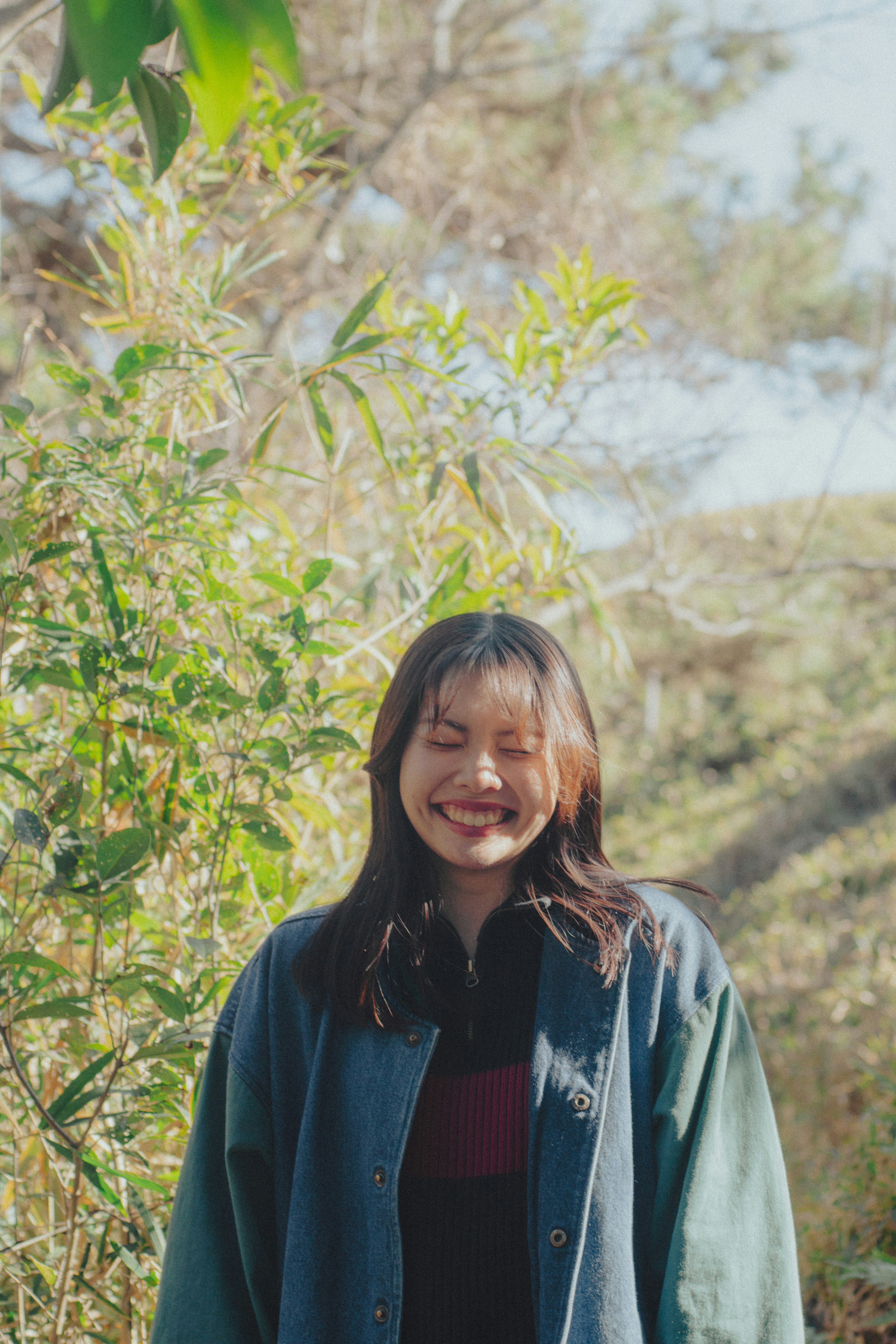 Femme souriante se tenant dans la nature entourée de plantes vertes