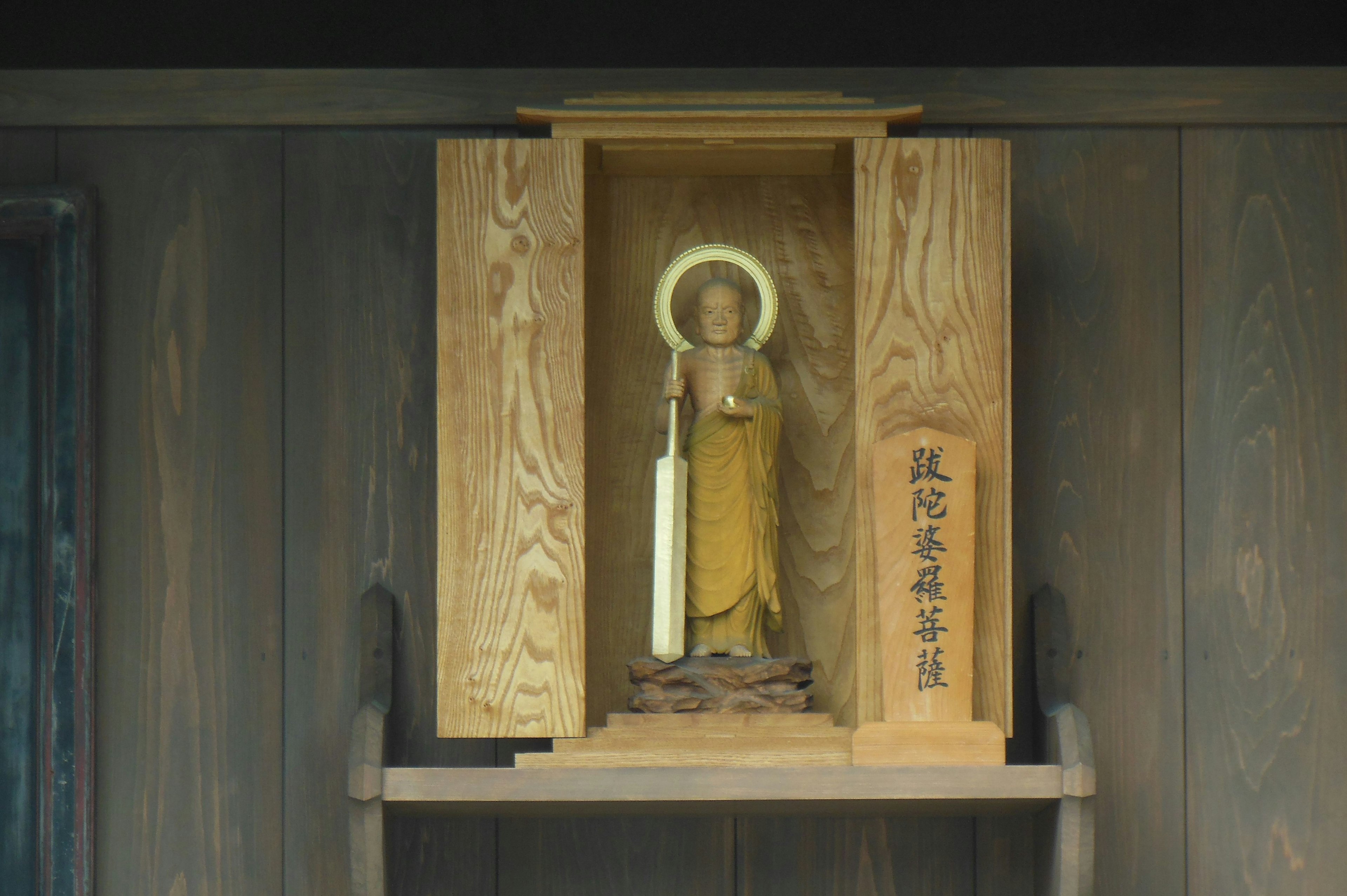 Wooden Buddha statue displayed in a wooden shrine