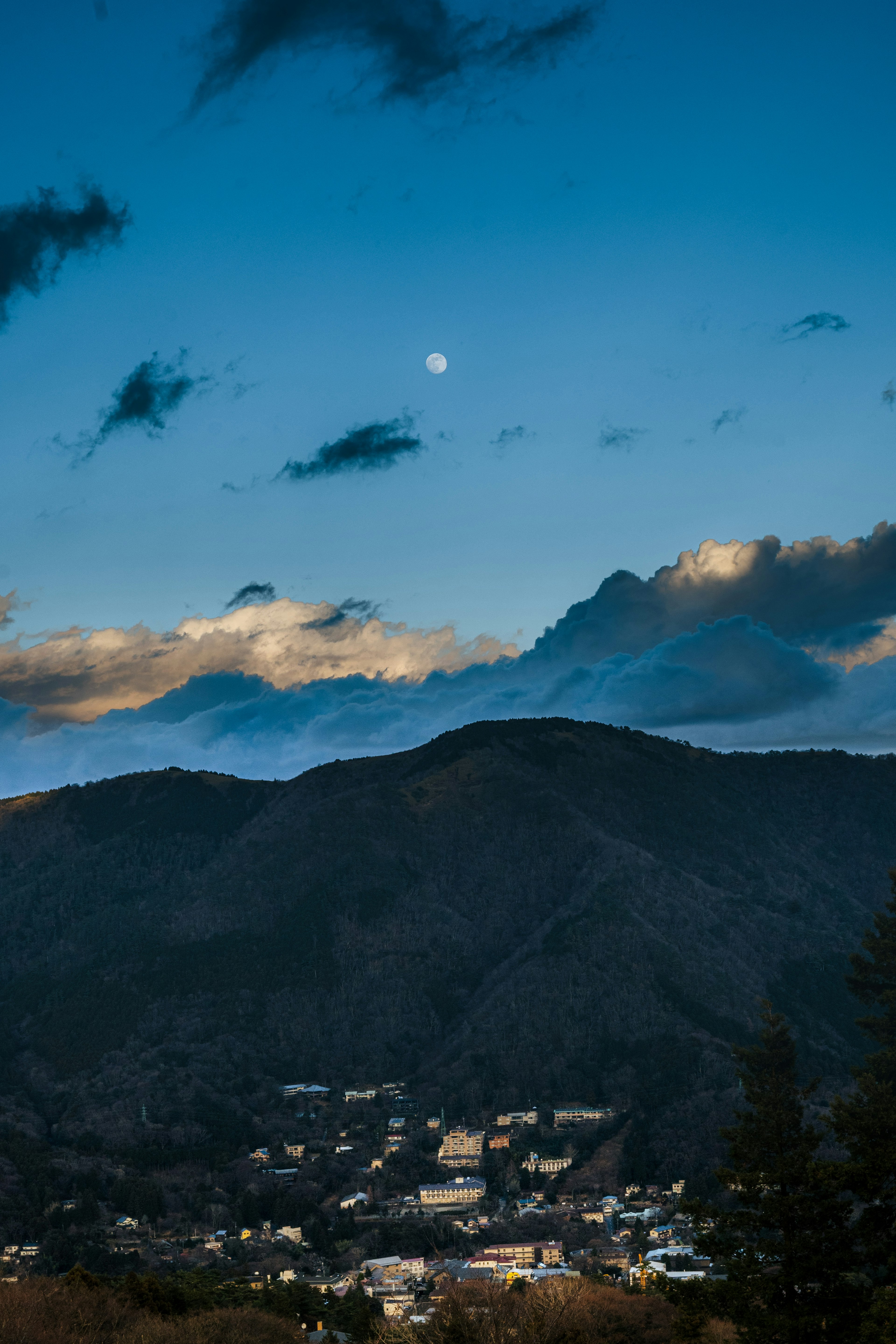 青い空に浮かぶ月と山々の美しい風景