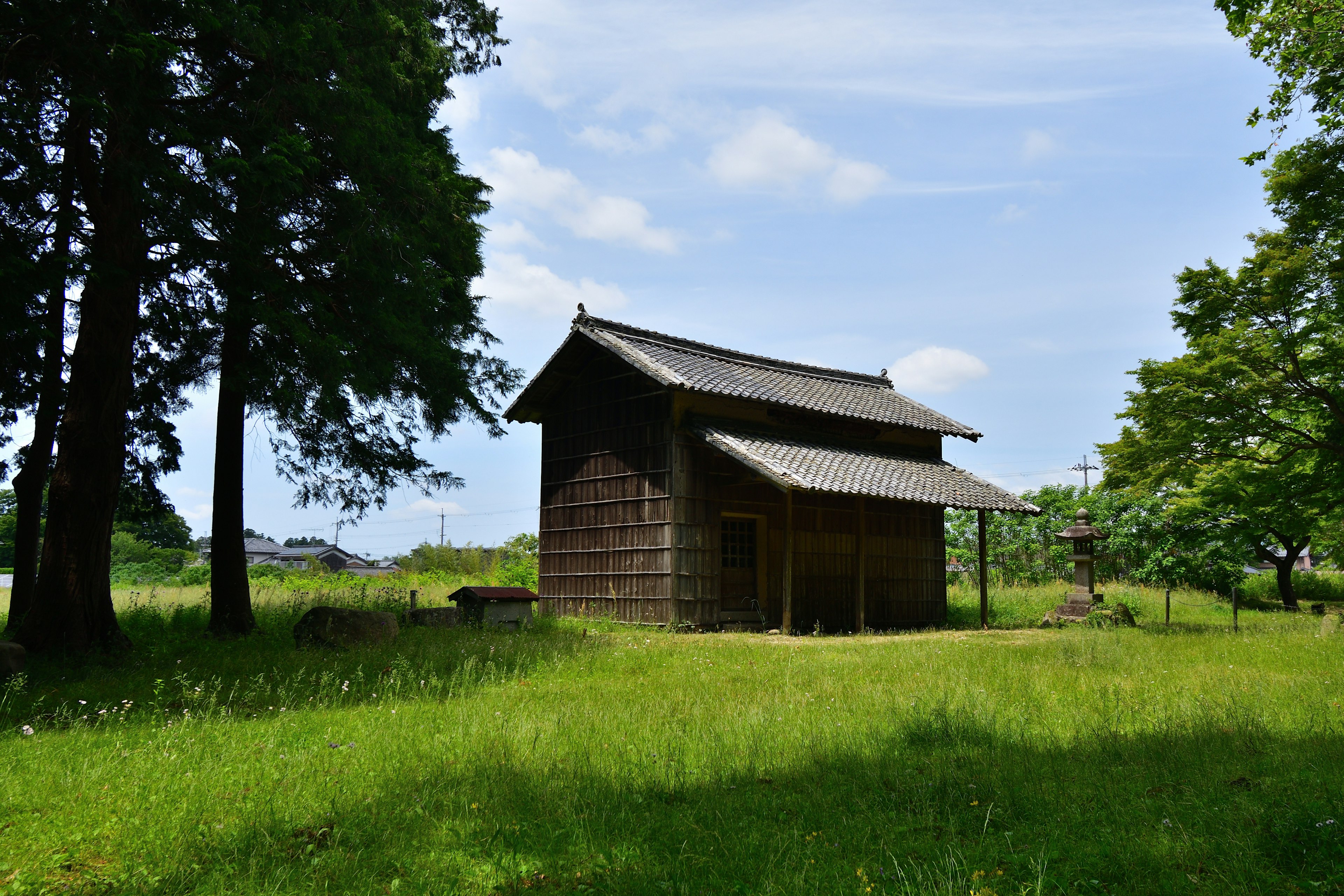 กระท่อมไม้ในทุ่งหญ้าสีเขียวใต้ท้องฟ้าสีฟ้า