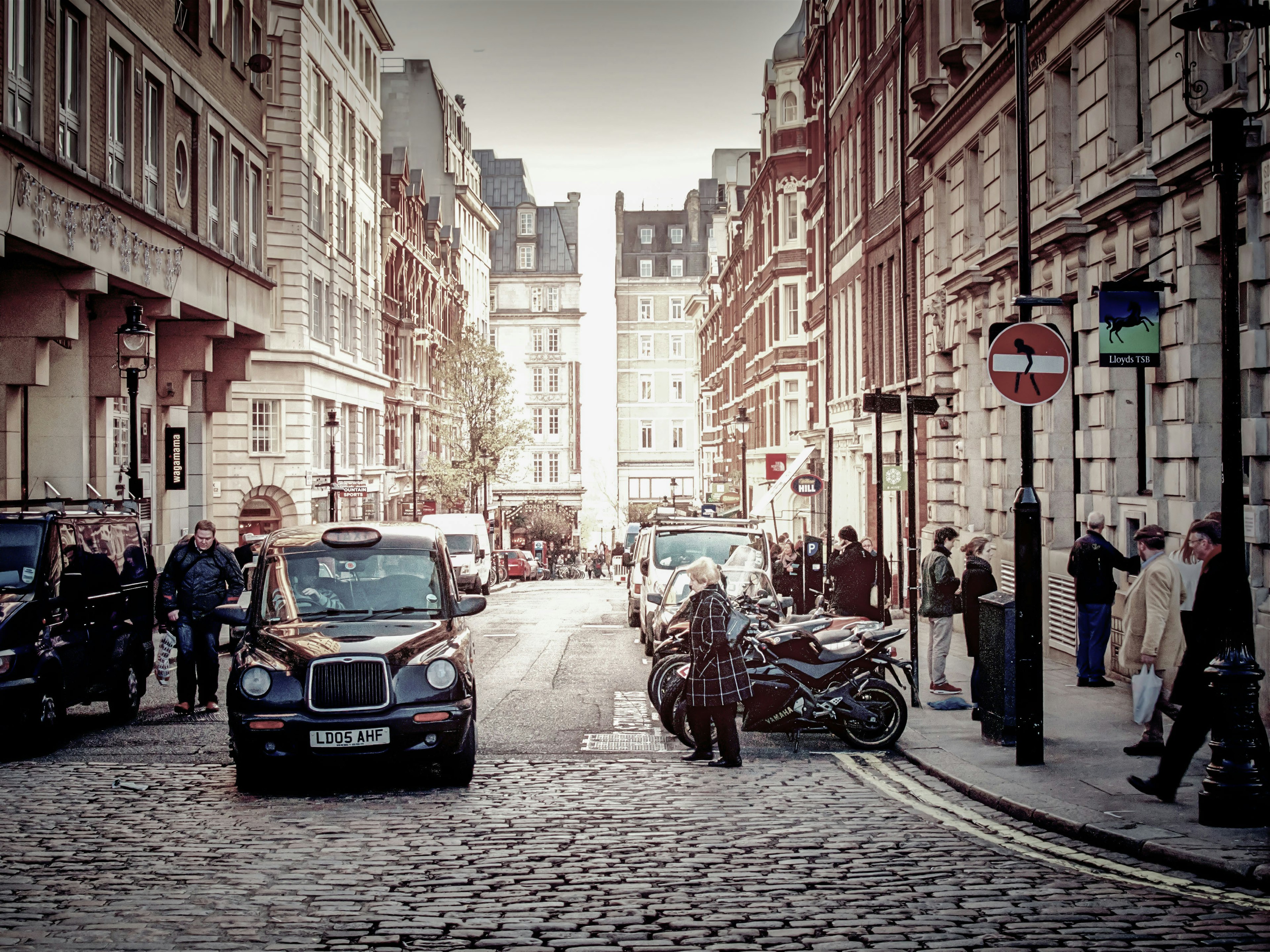 Una calle adoquinada con coches y peatones