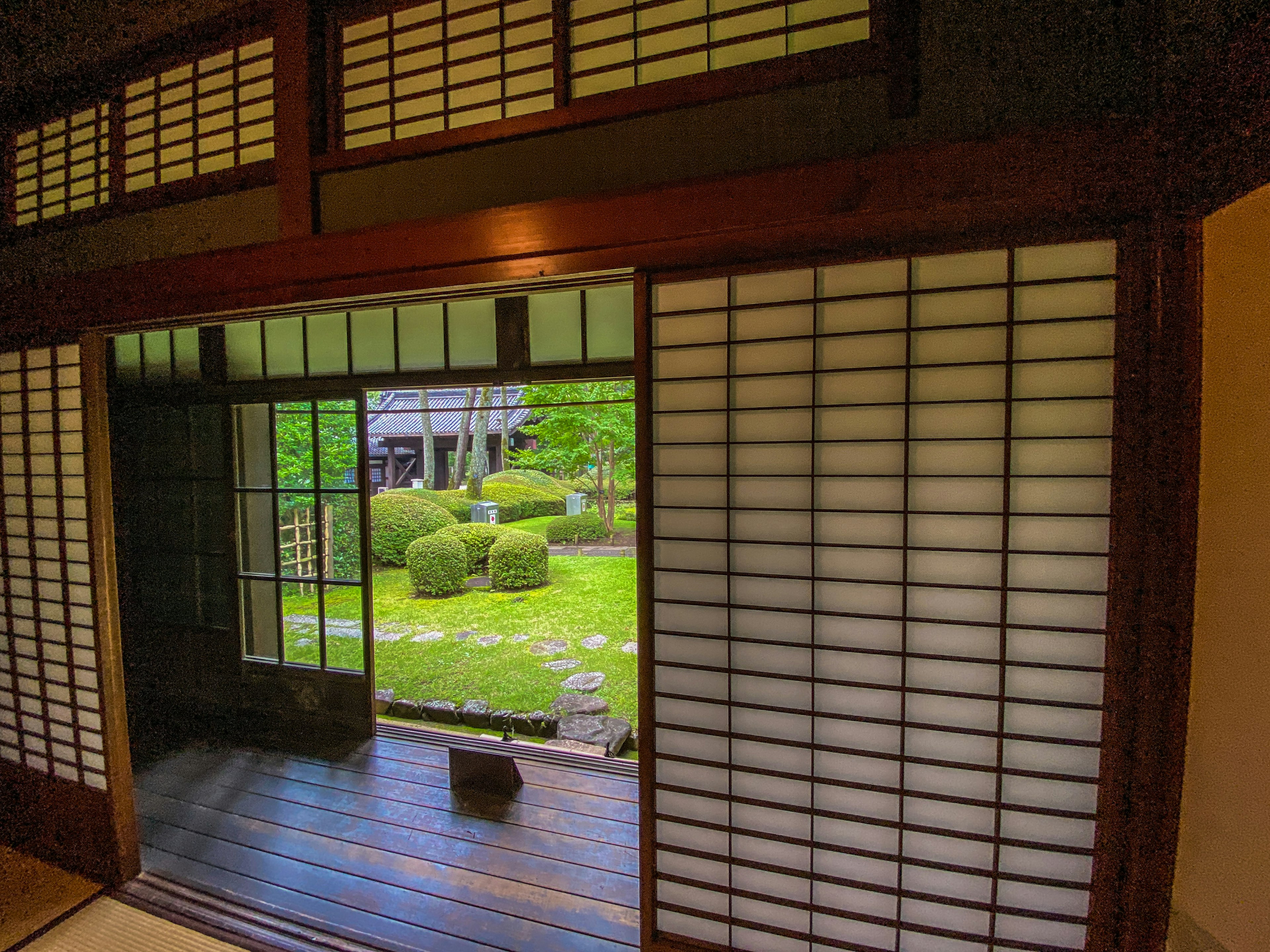 Vista del interior de una casa tradicional japonesa con vista a un jardín que presenta shoji y marcos de madera