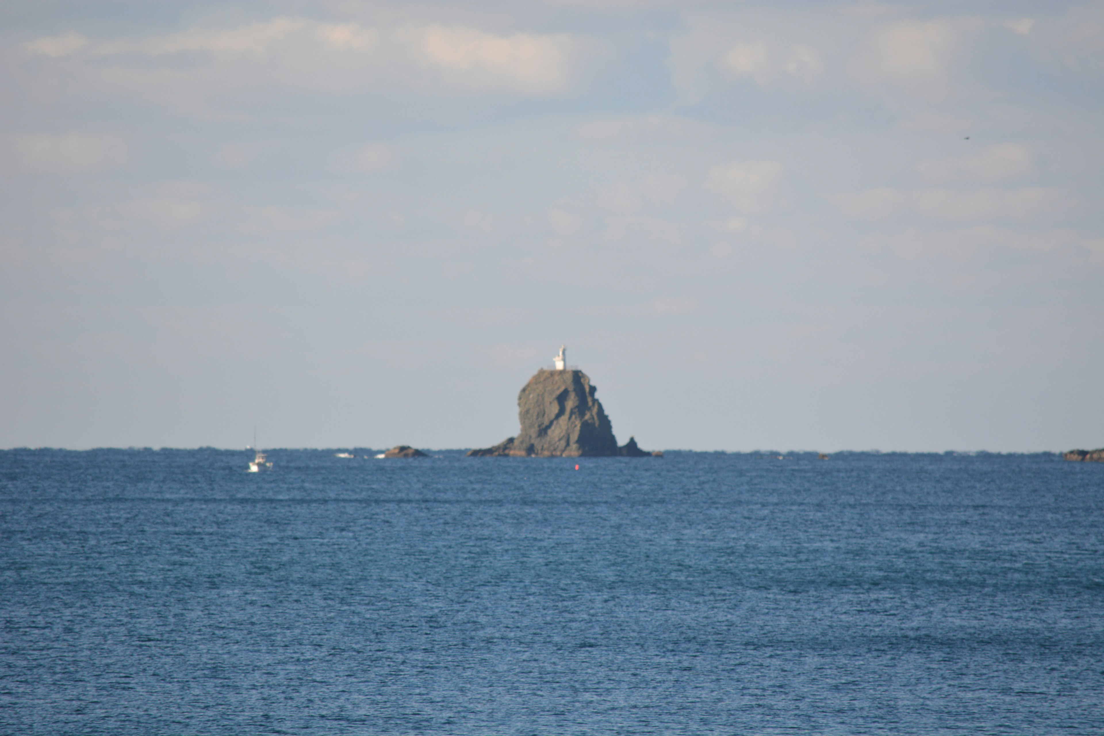 Piccolo scoglio con un faro nell'oceano blu