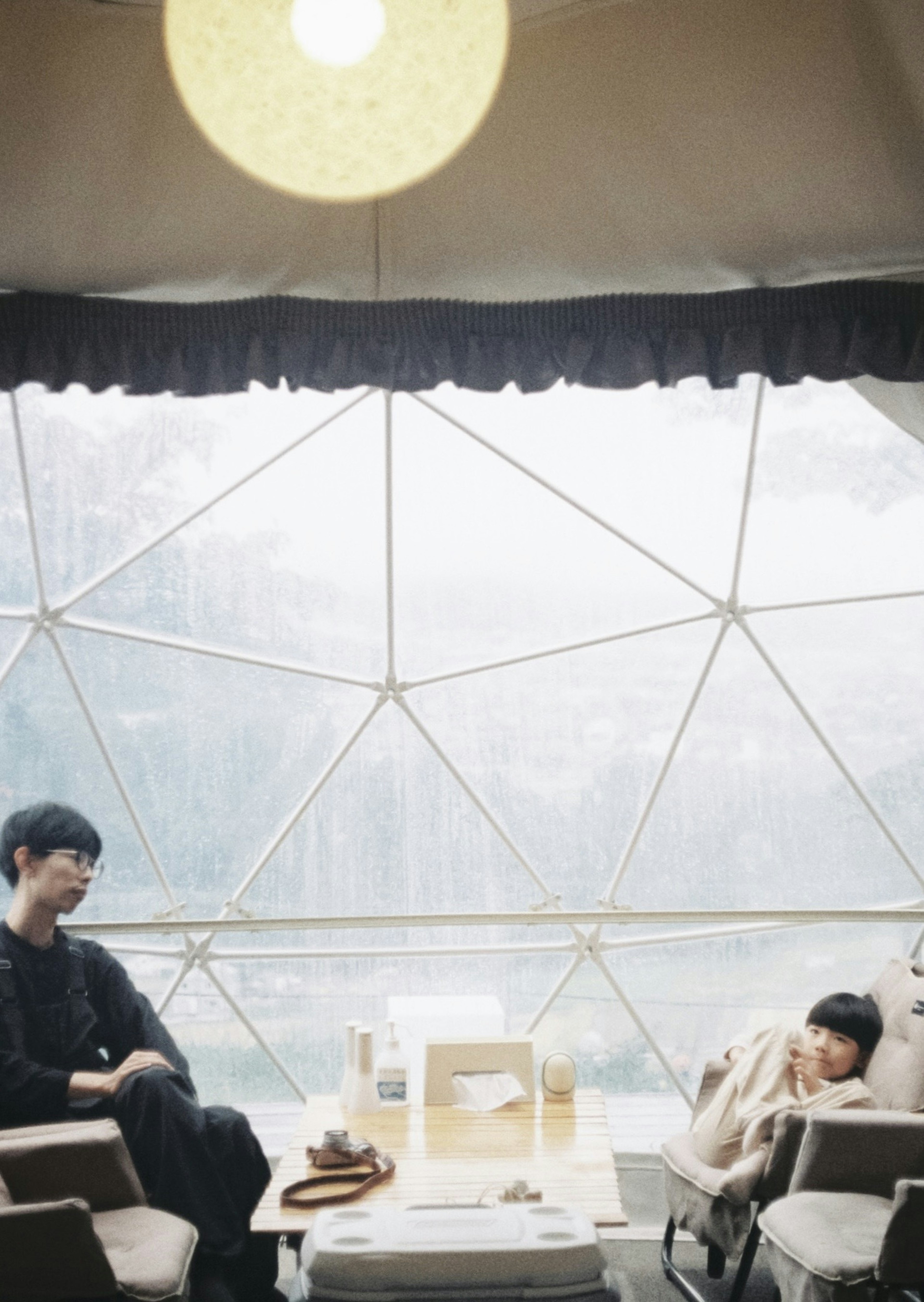 Cozy space with two people relaxing and a table inside a glass dome