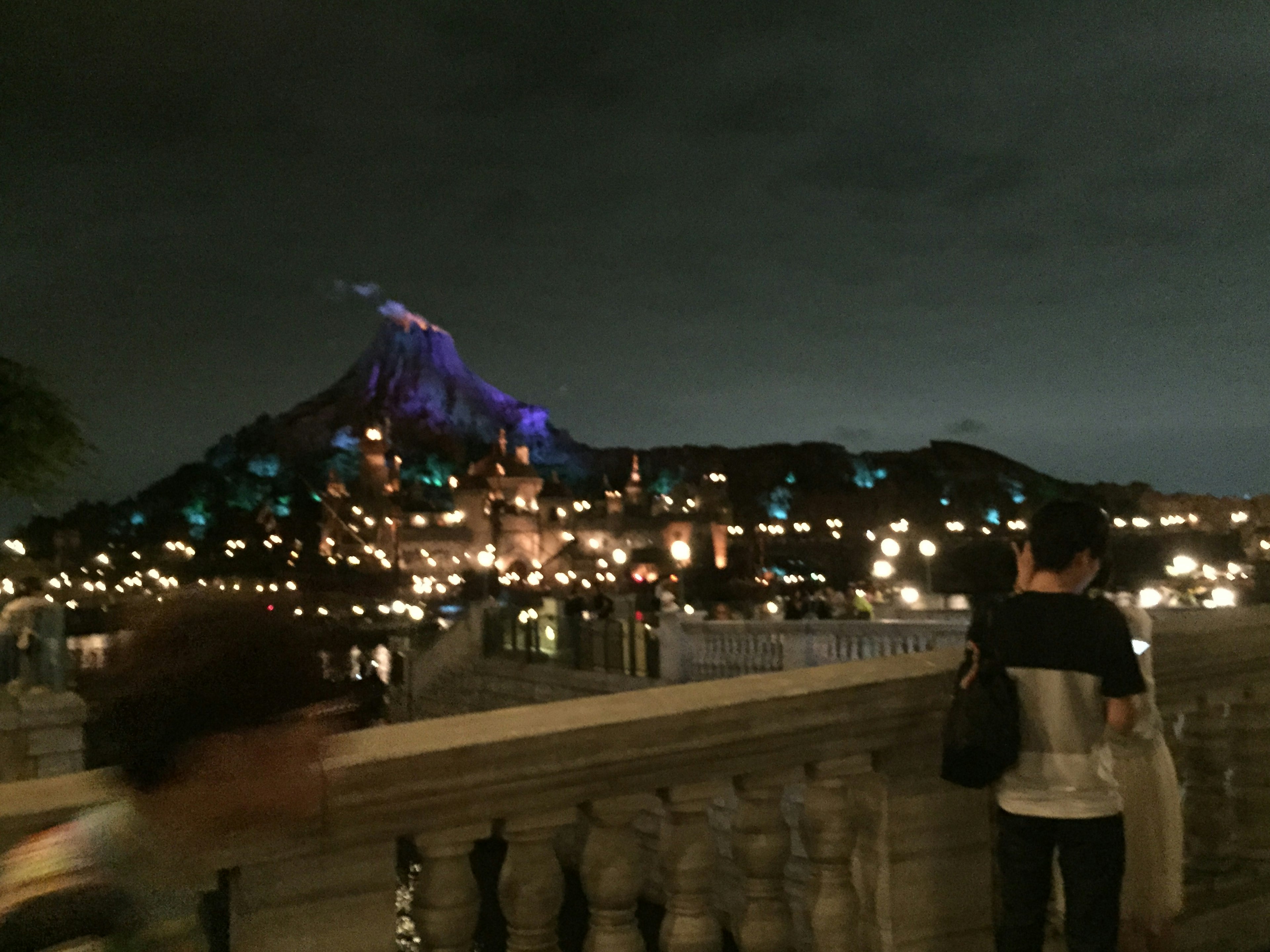 Scène nocturne avec une montagne et des bâtiments illuminés