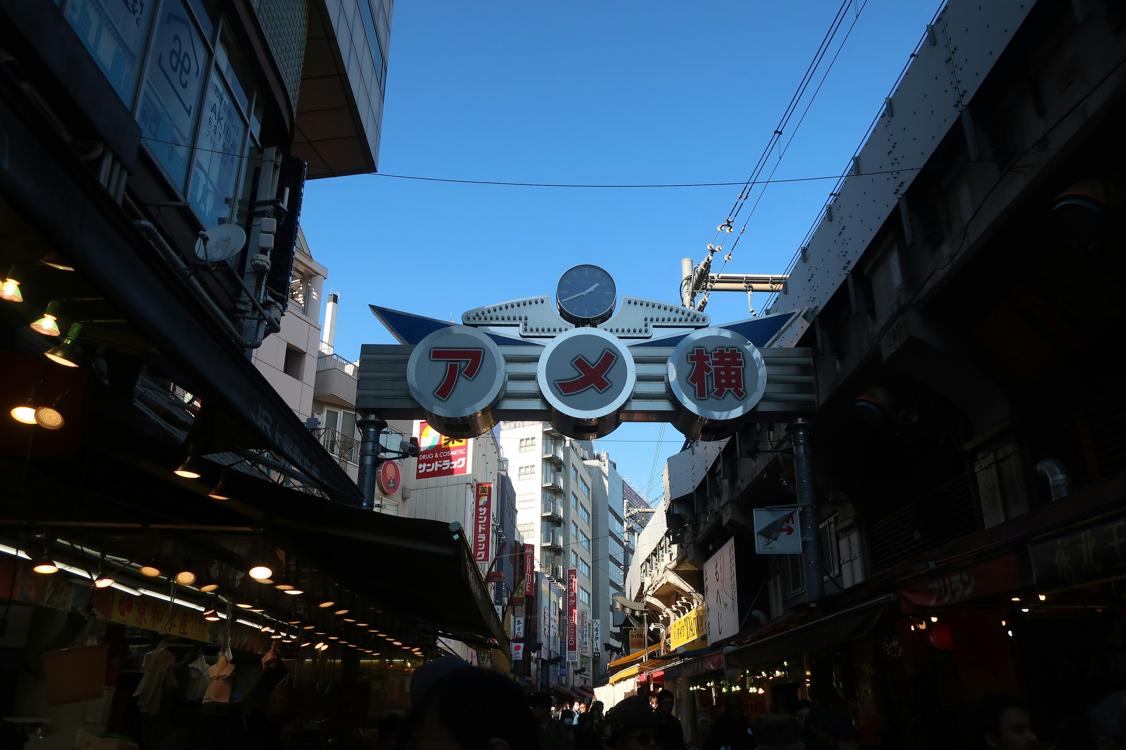 アメ横の賑やかな商店街の入口青空と高い建物が見える