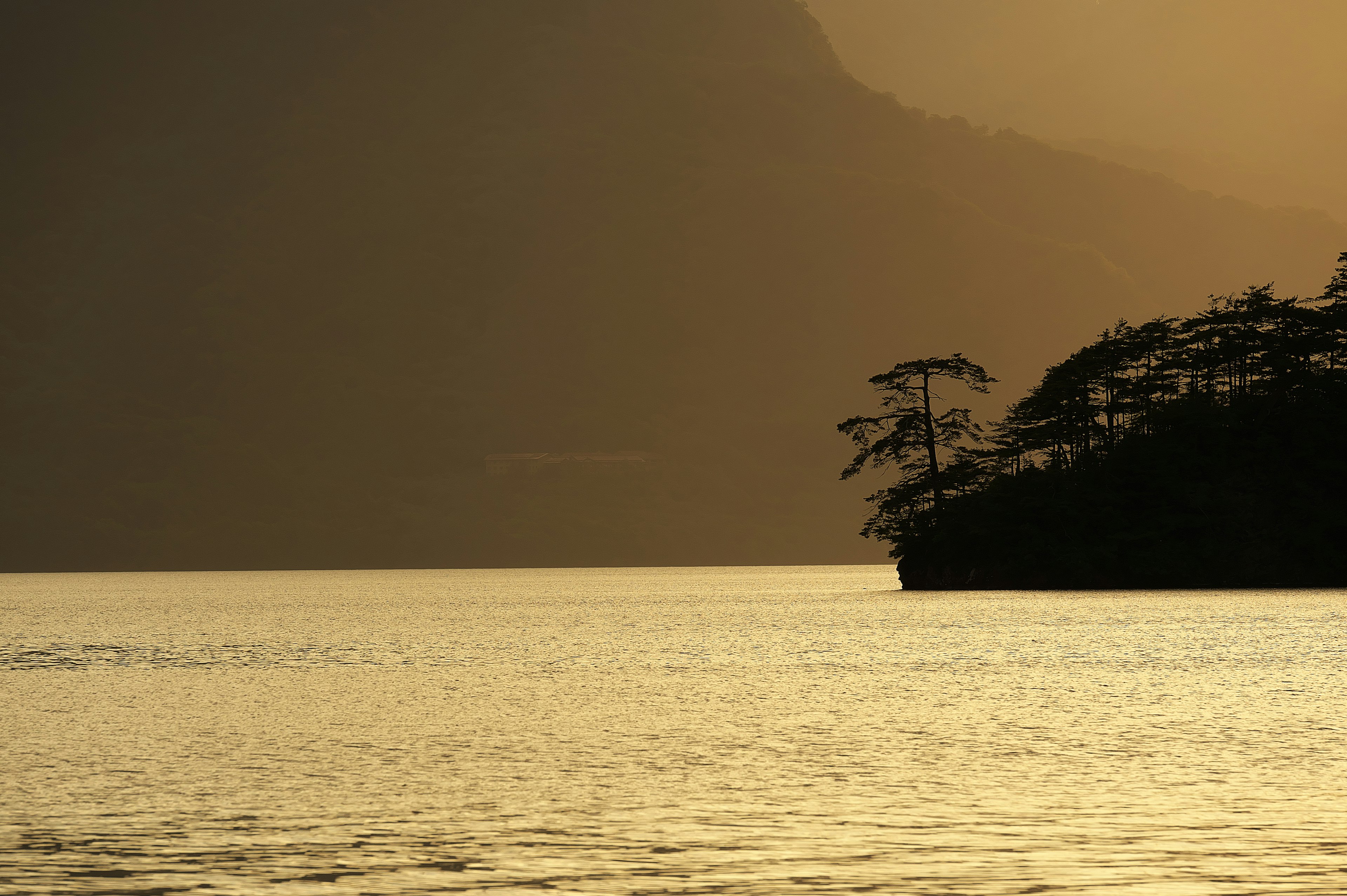 夕暮れの湖と山のシルエットが映える風景