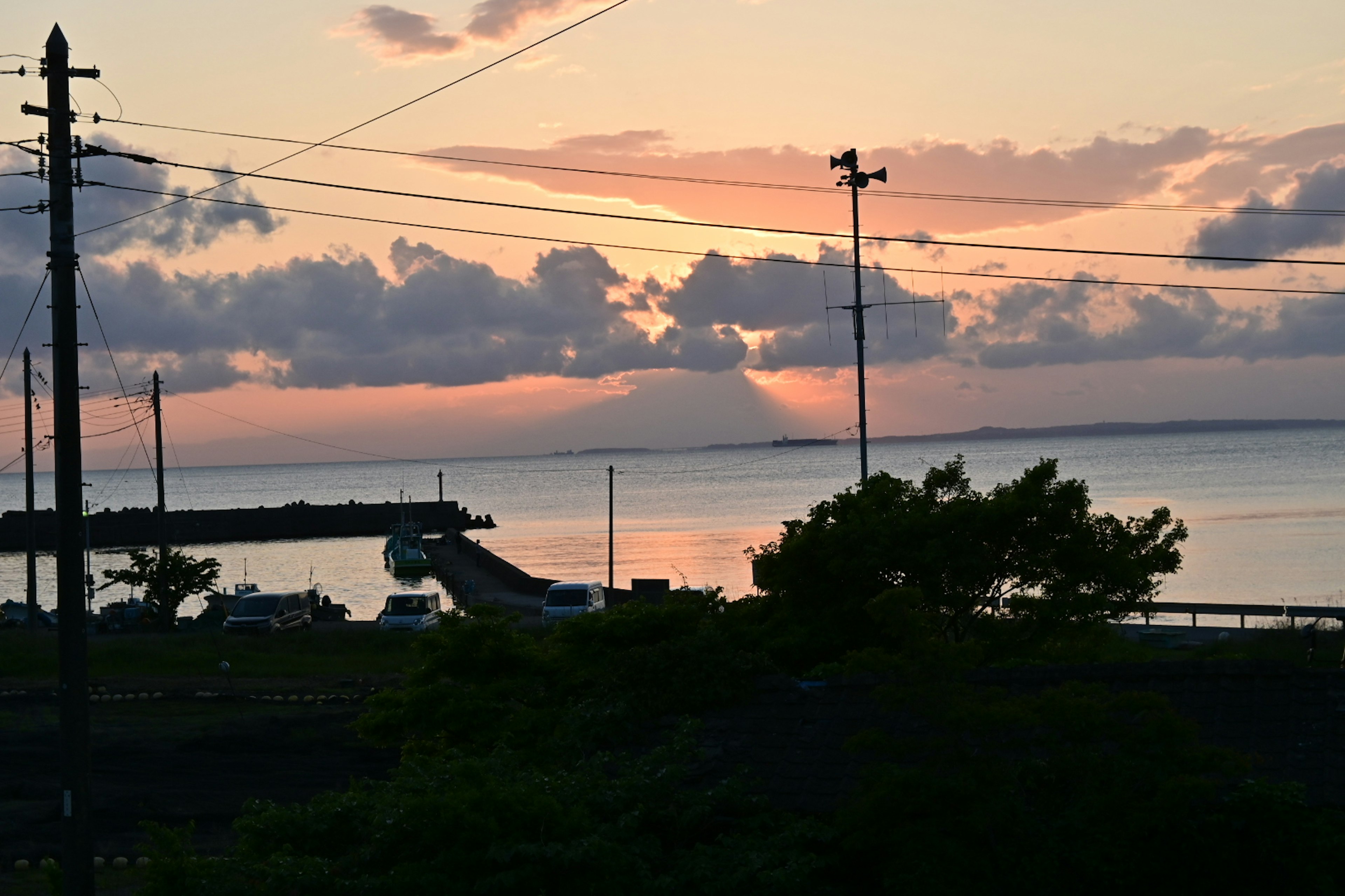 夕焼けの海辺の風景 船が停泊する桟橋と雲が広がる空