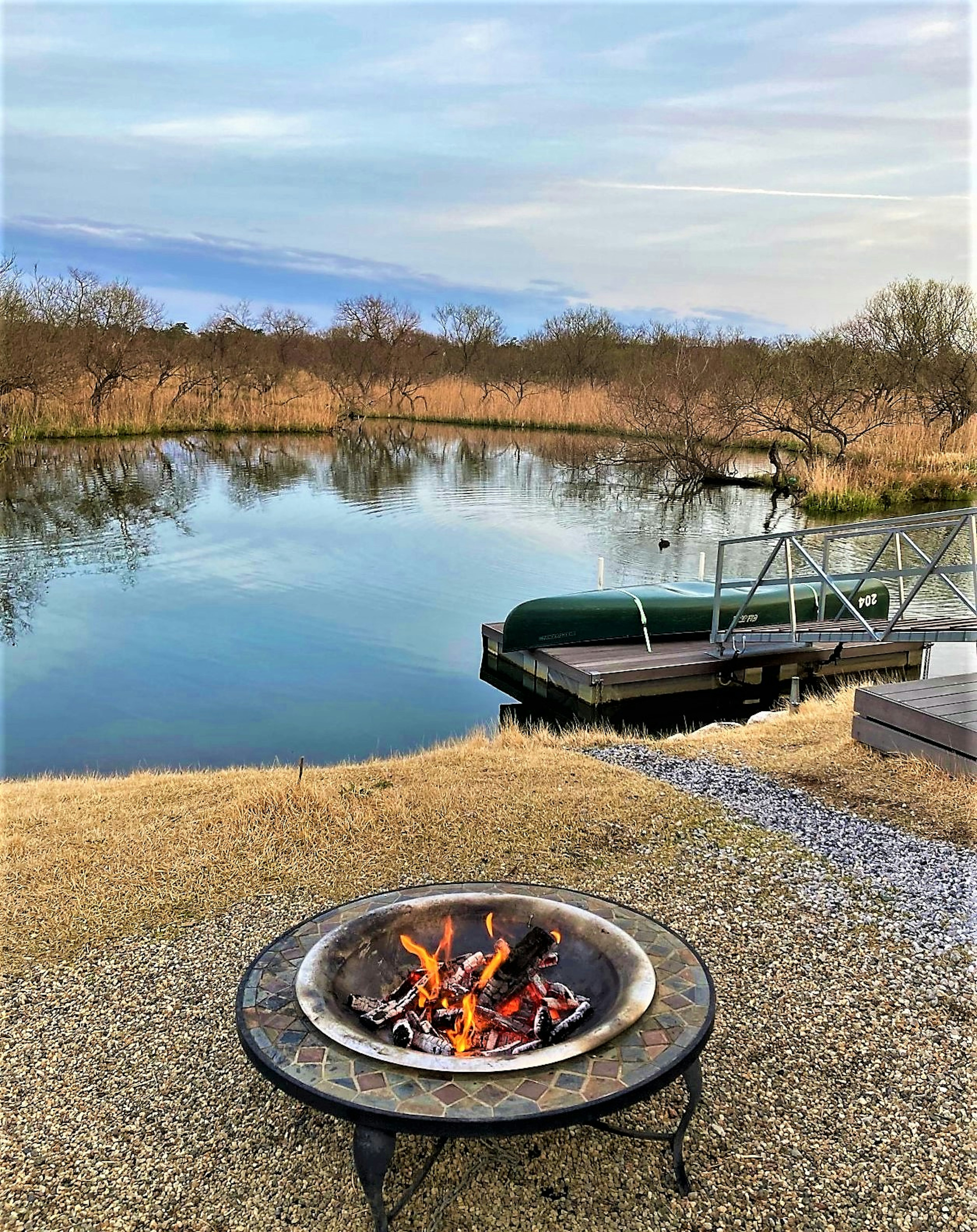 Foyer de feu au bord d'un lac serein avec un quai de bateau vert