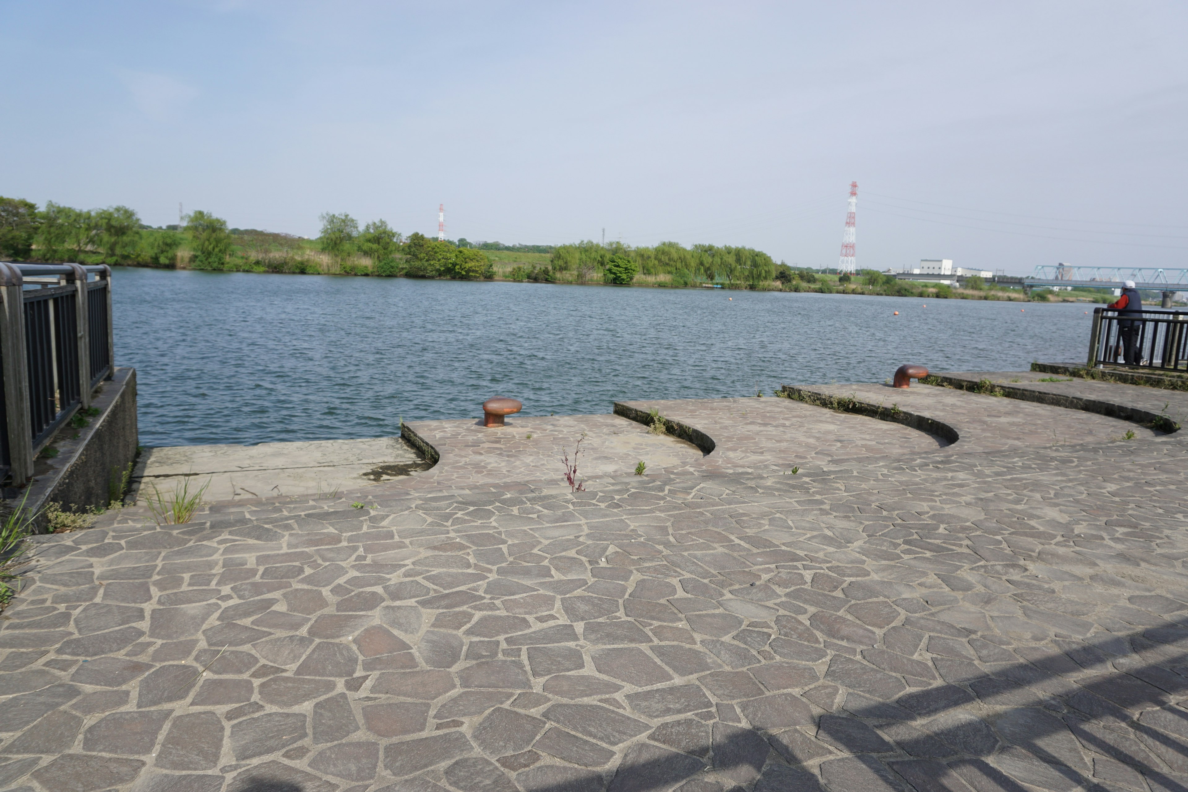 Zone pavée de pierres au bord d'une rivière calme avec des arbres verts