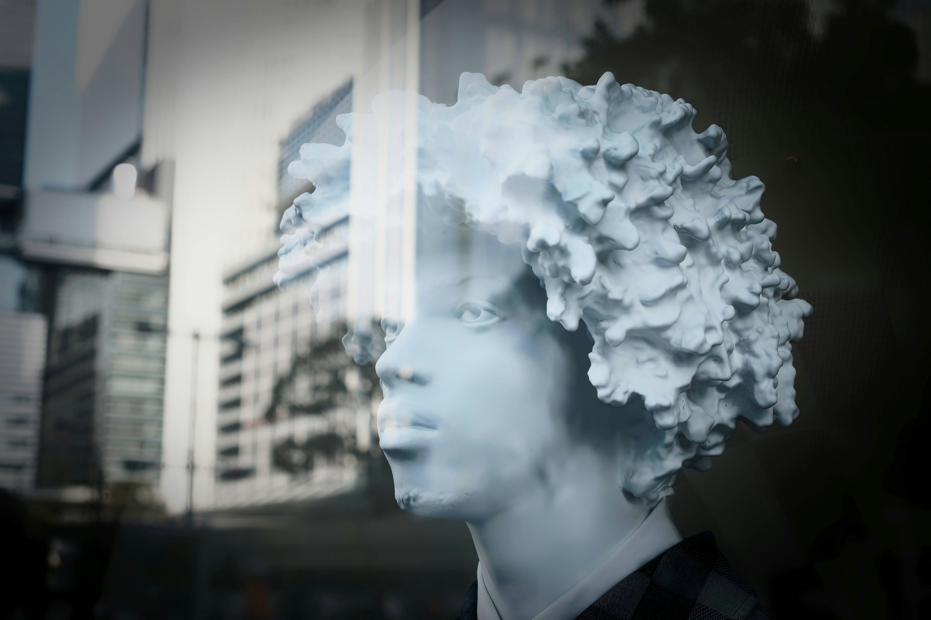 White sculptural head with unique hairstyle against urban backdrop