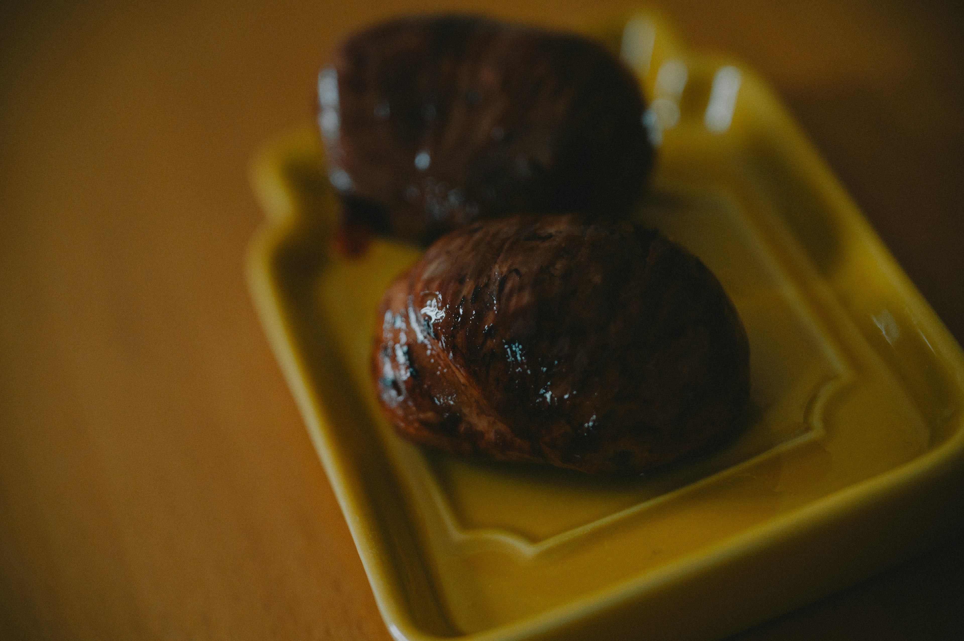 Two brown pastries on a yellow plate