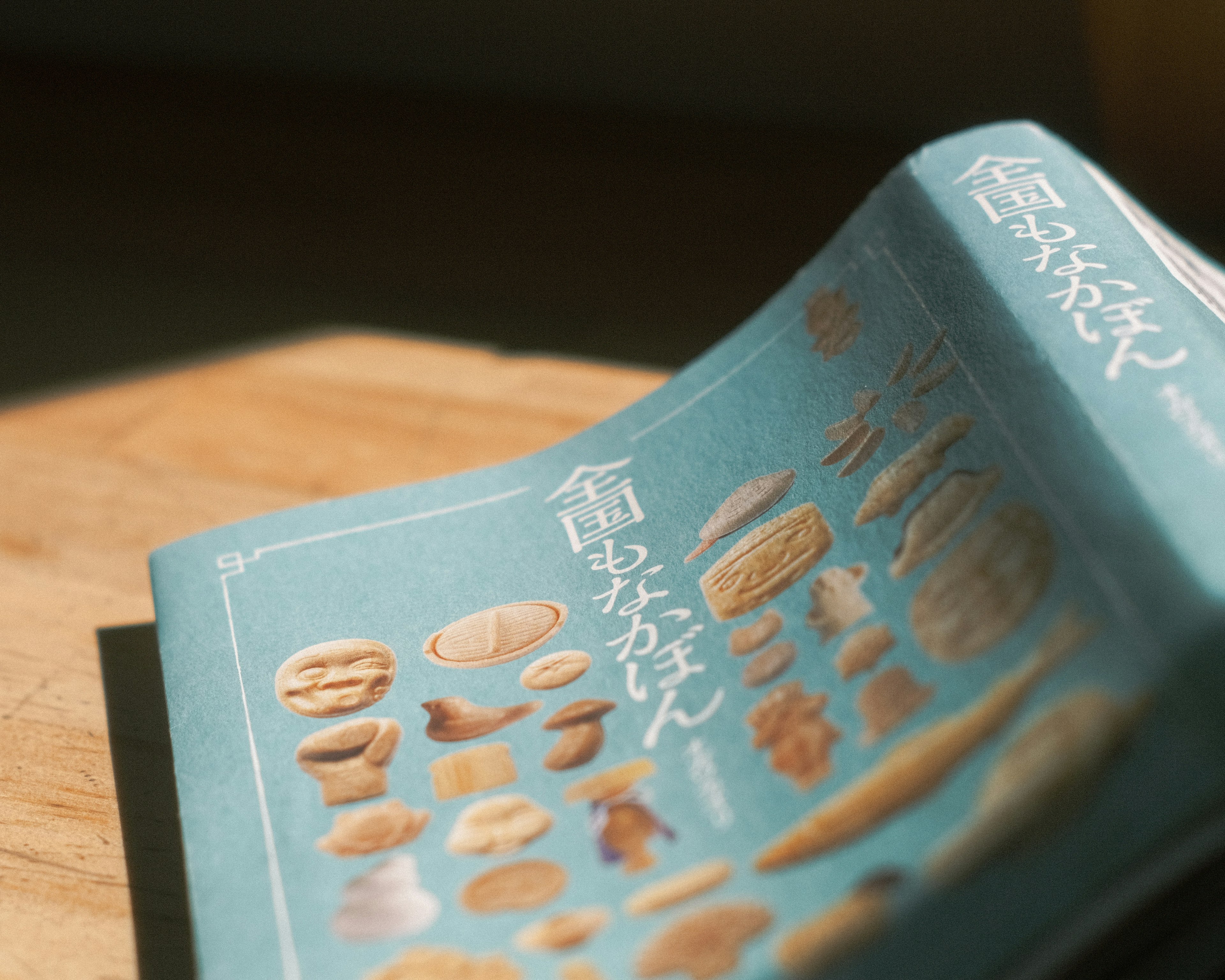 A book with a blue cover resting on a wooden table featuring various shapes of bread on its pages