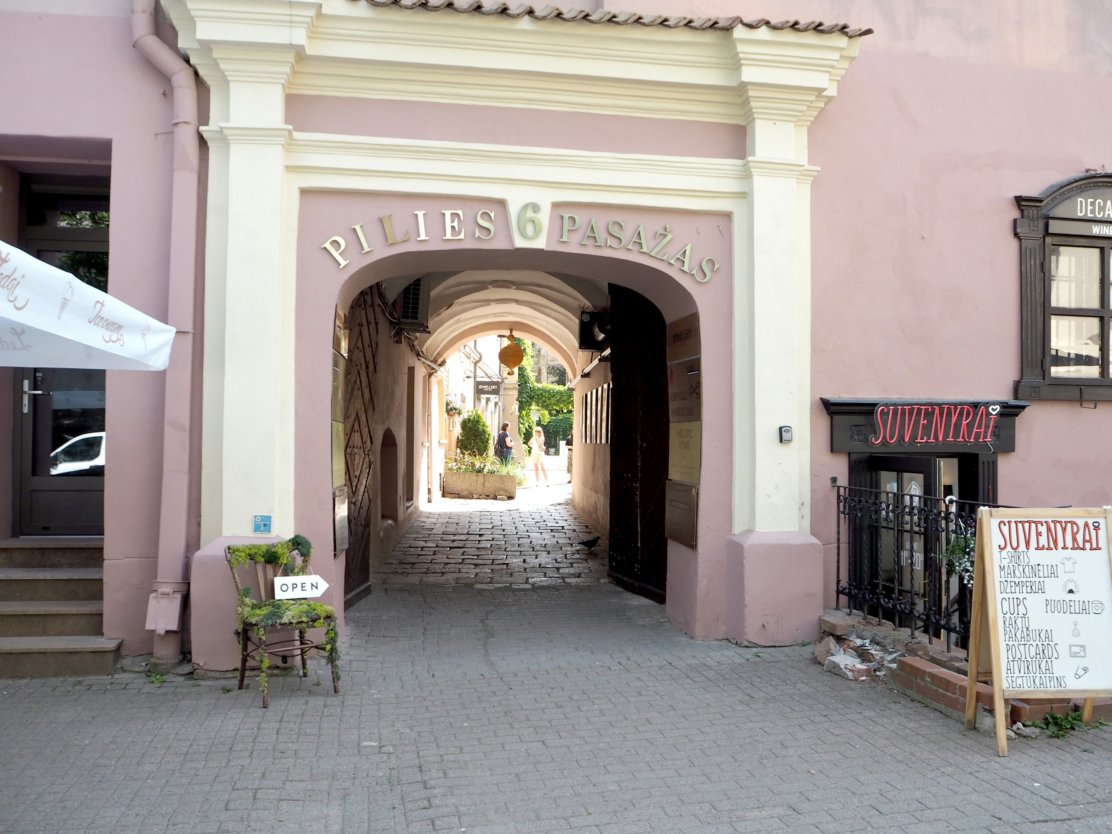 Archway entrance with pink walls leading to a street