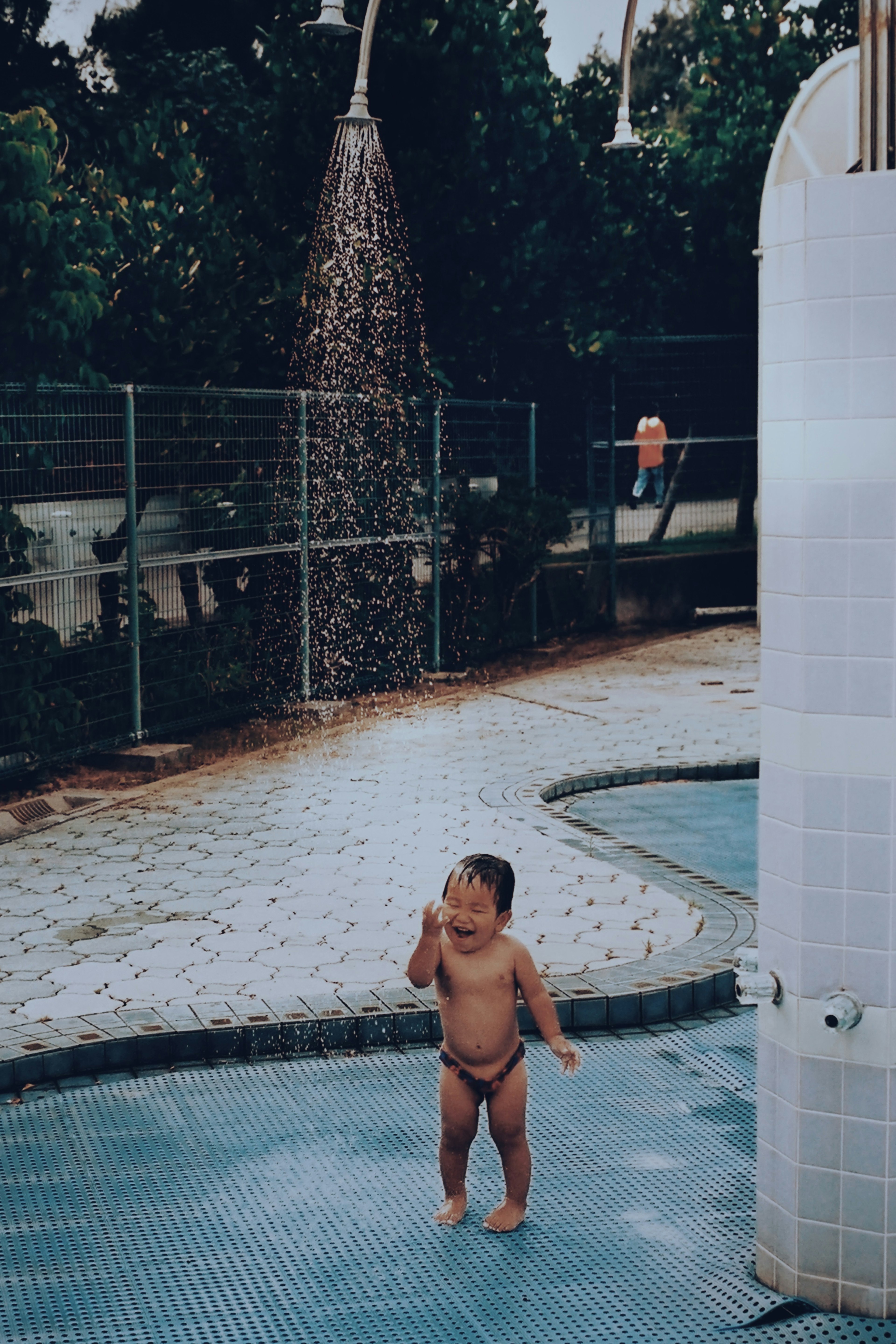 Niño jugando en una piscina con una ducha que rocía agua