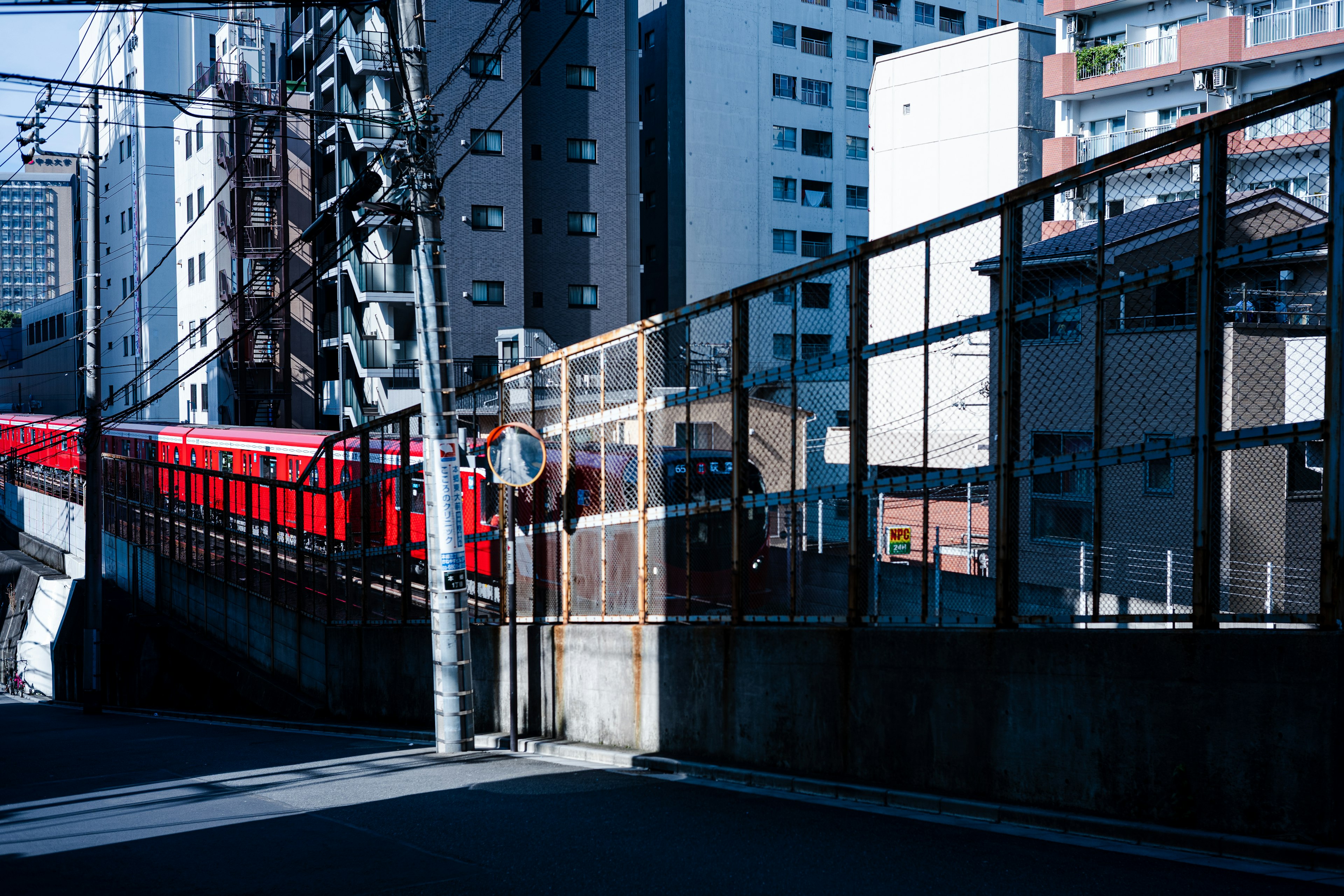 赤い電車が高架の線路を走る都市の風景