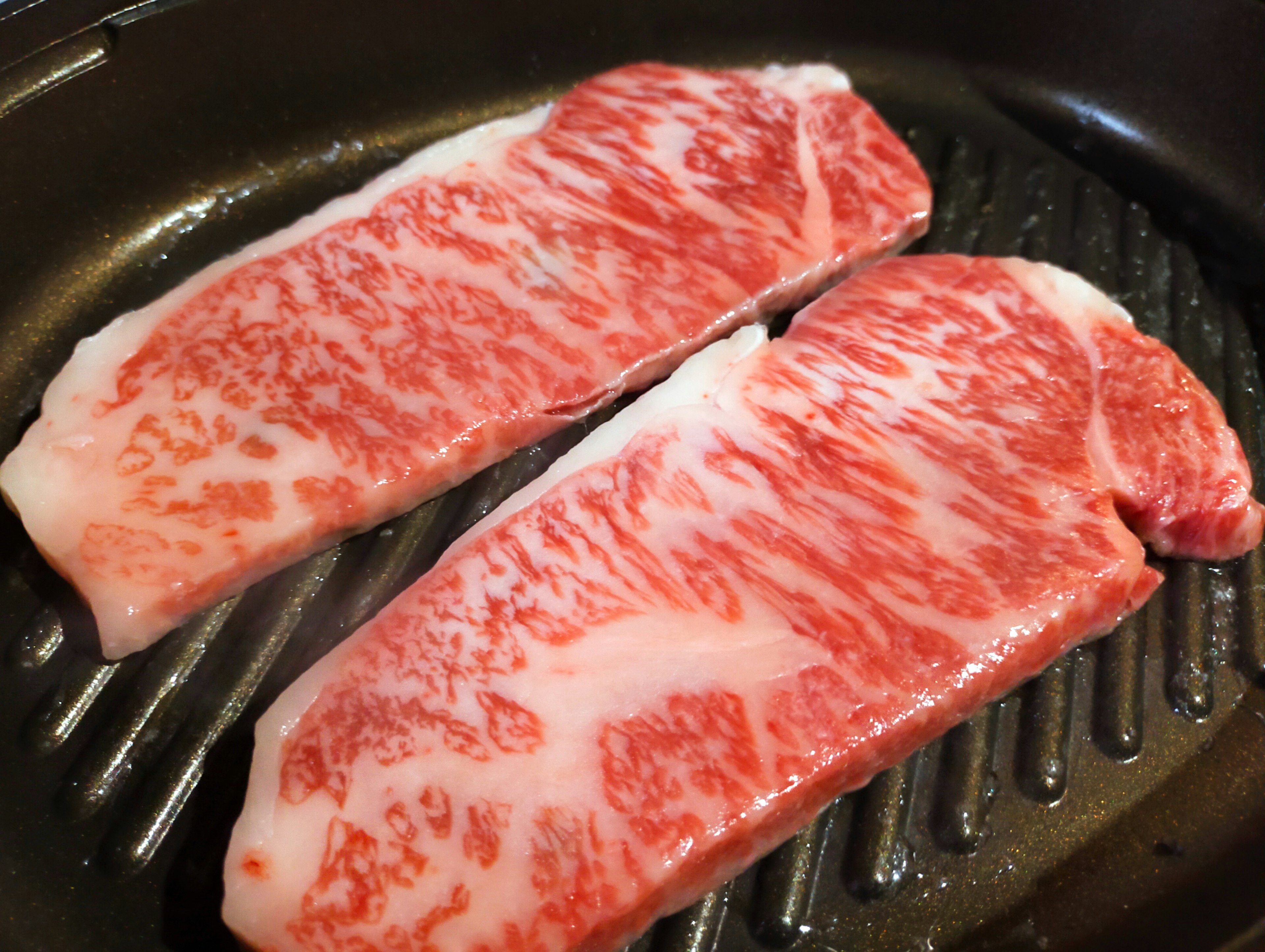 Two marbled slices of Wagyu beef on a grill plate