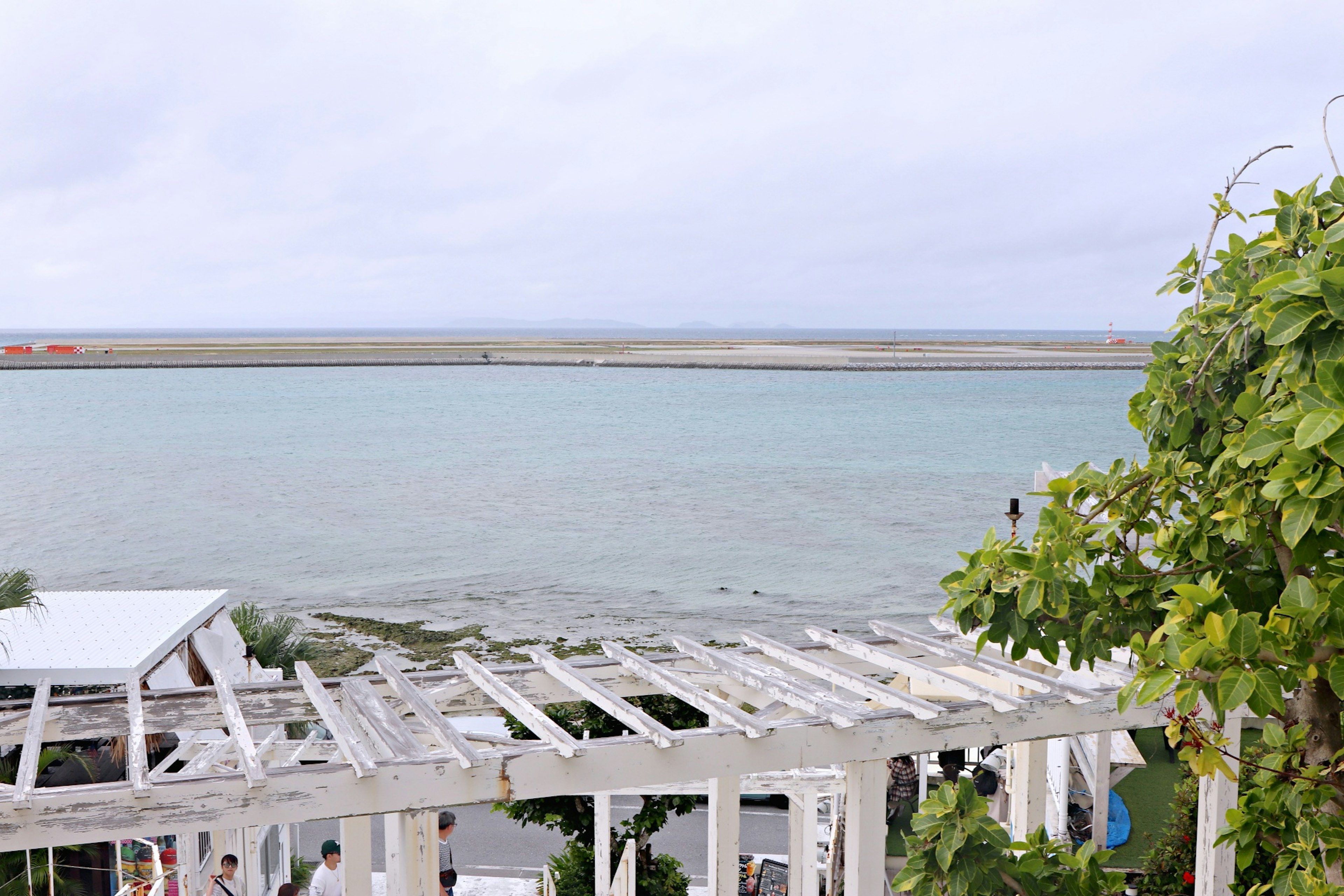 海と空の青が広がる風景 白いパーゴラと緑の植物がある