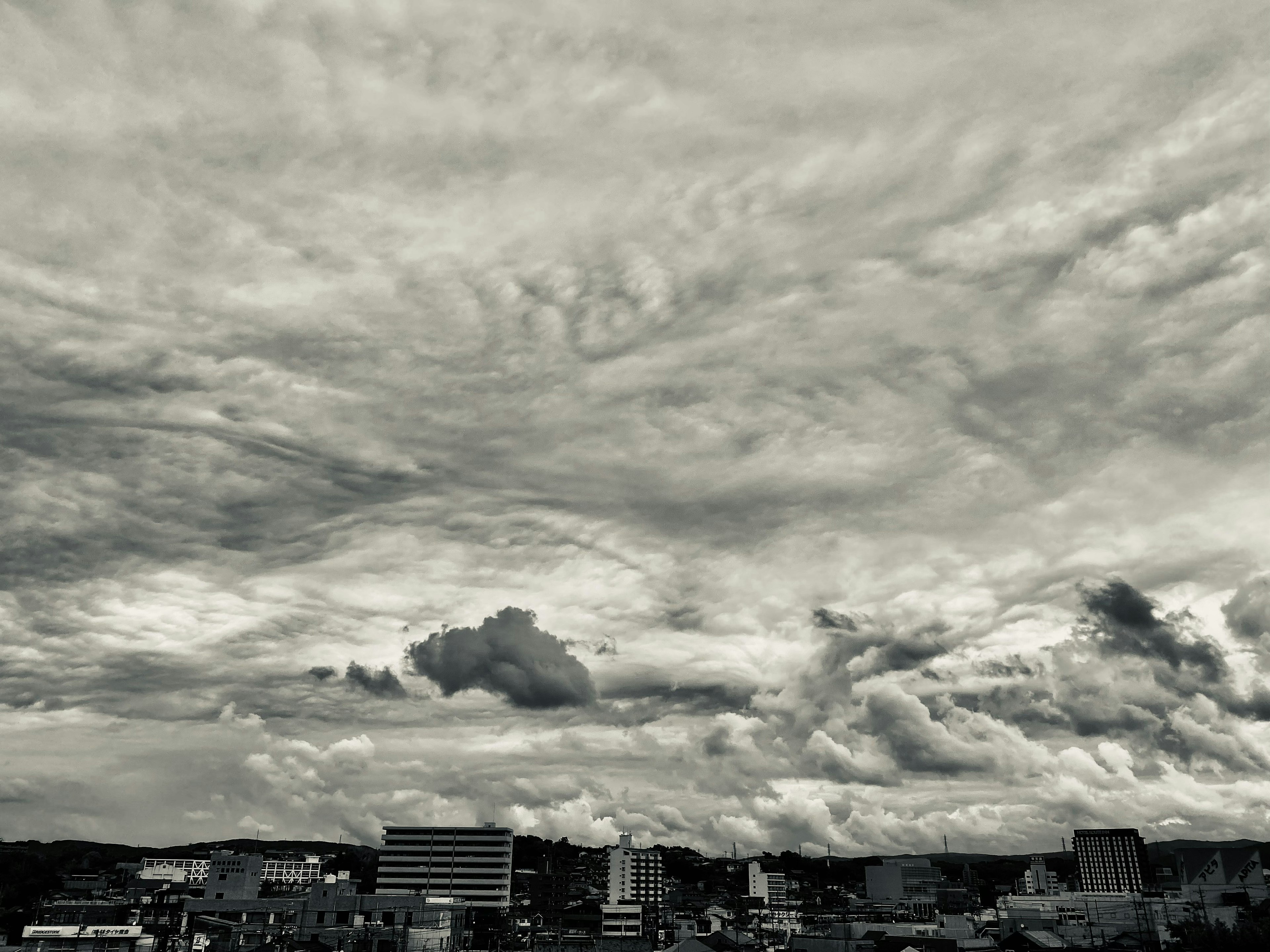 Cielo in bianco e nero con nuvole drammatiche e skyline di città