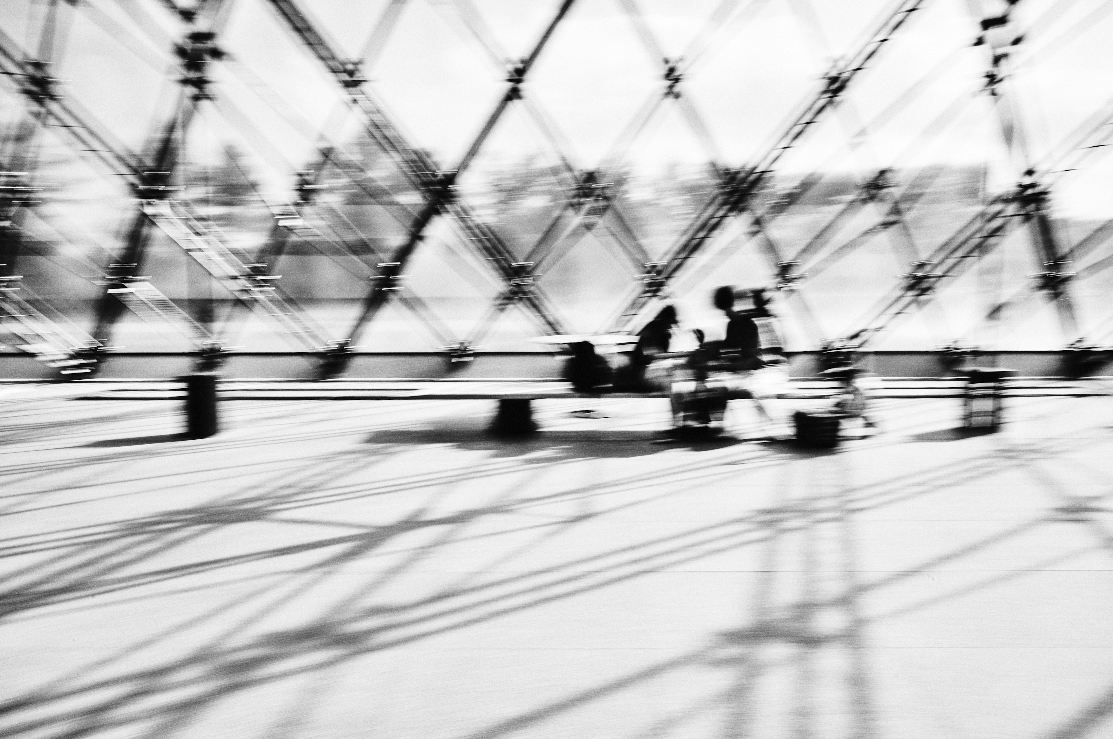 Blurred black and white photo of the Louvre Museum exterior with intersecting shadows