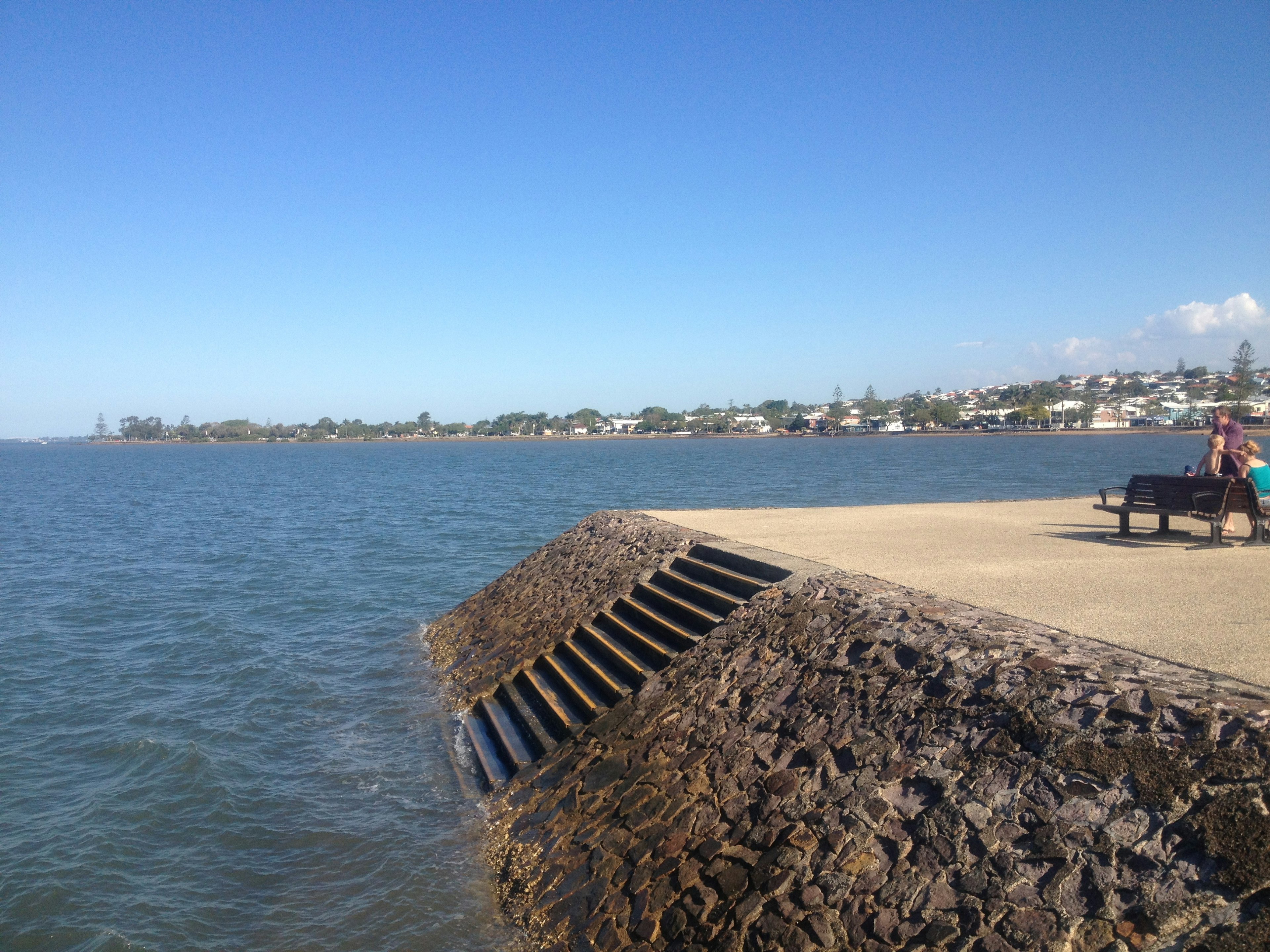 Coastal view featuring a bench and a breakwater