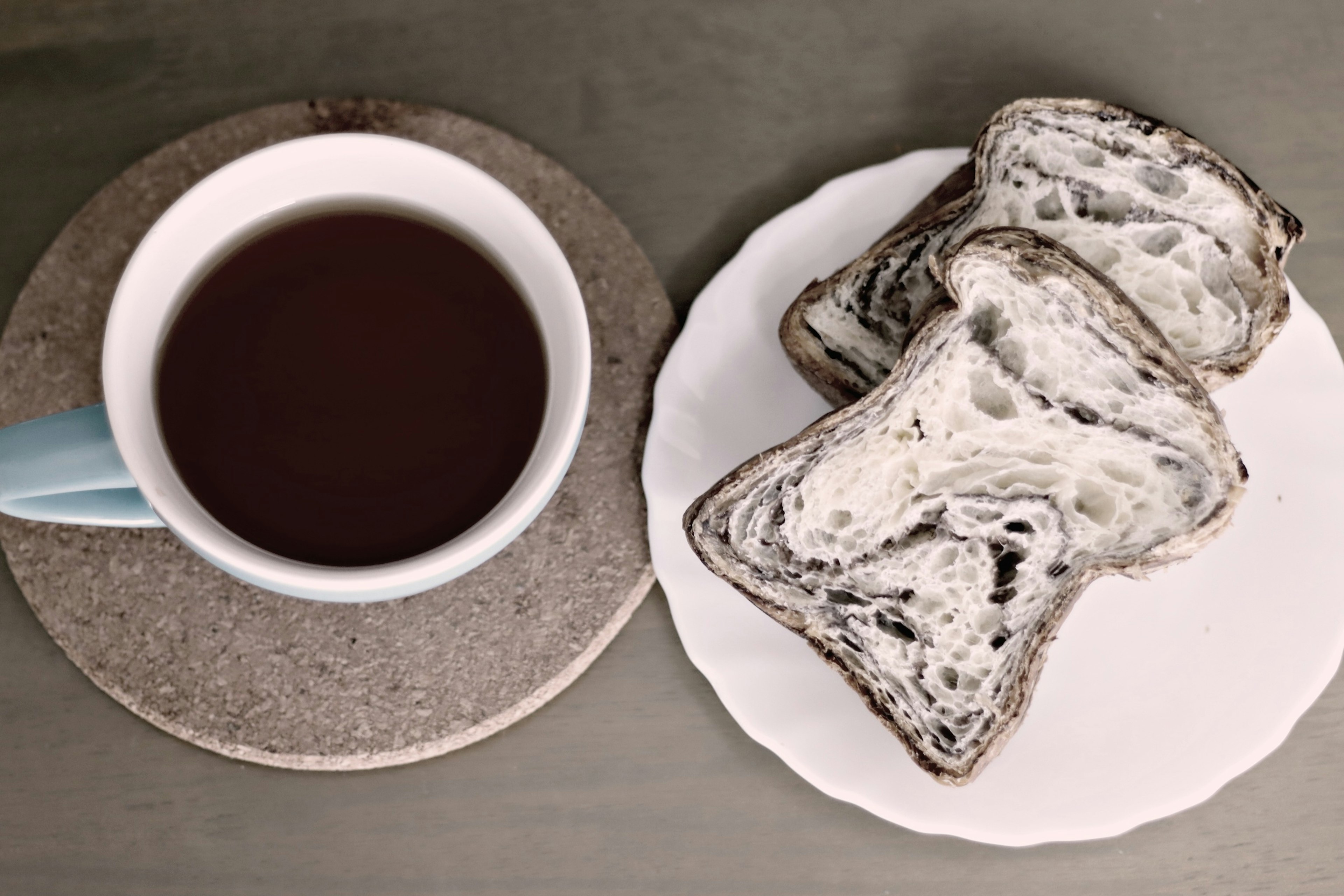 Cup of coffee next to slices of marble bread on a white plate