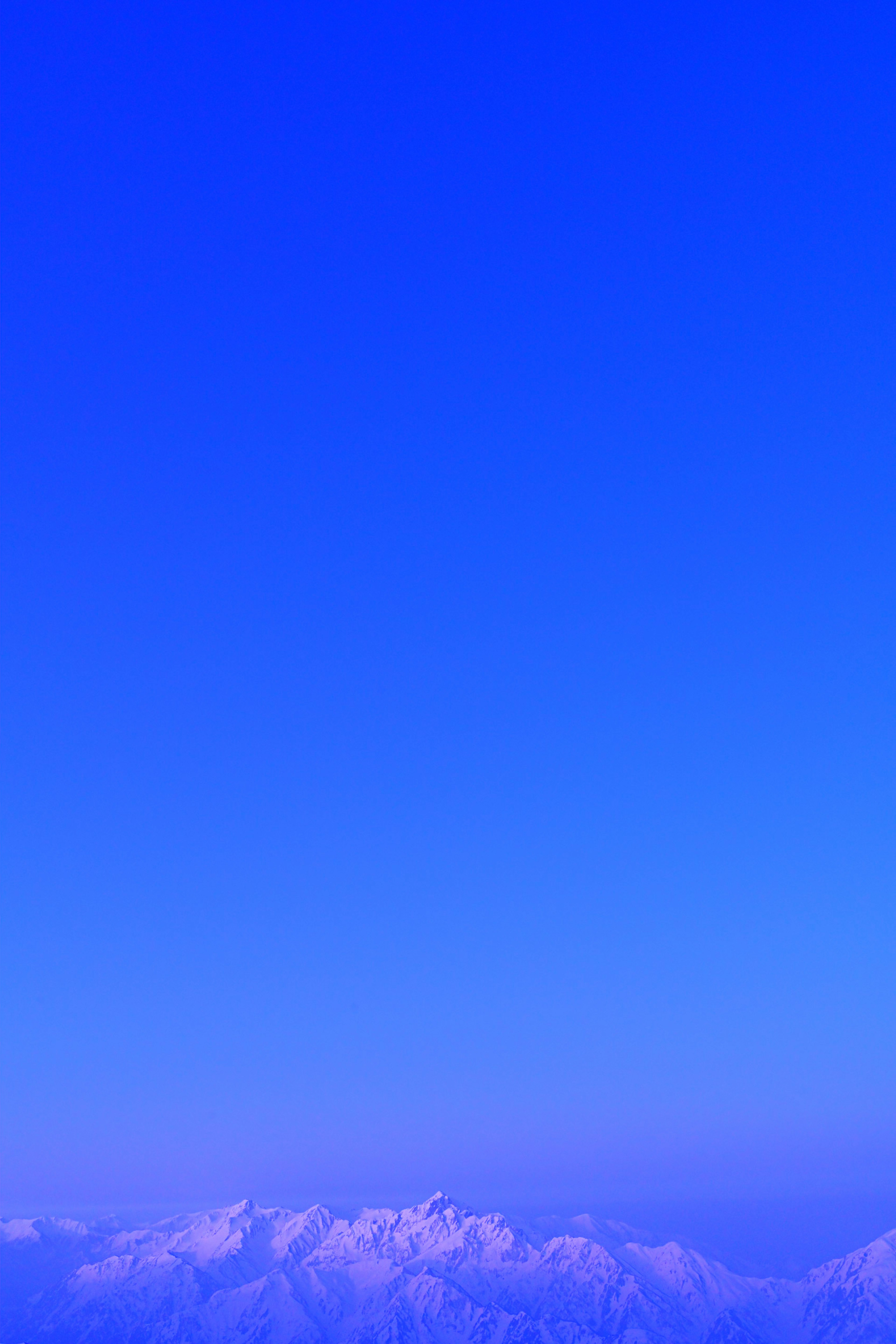 A blue sky with snow-capped mountains in the background