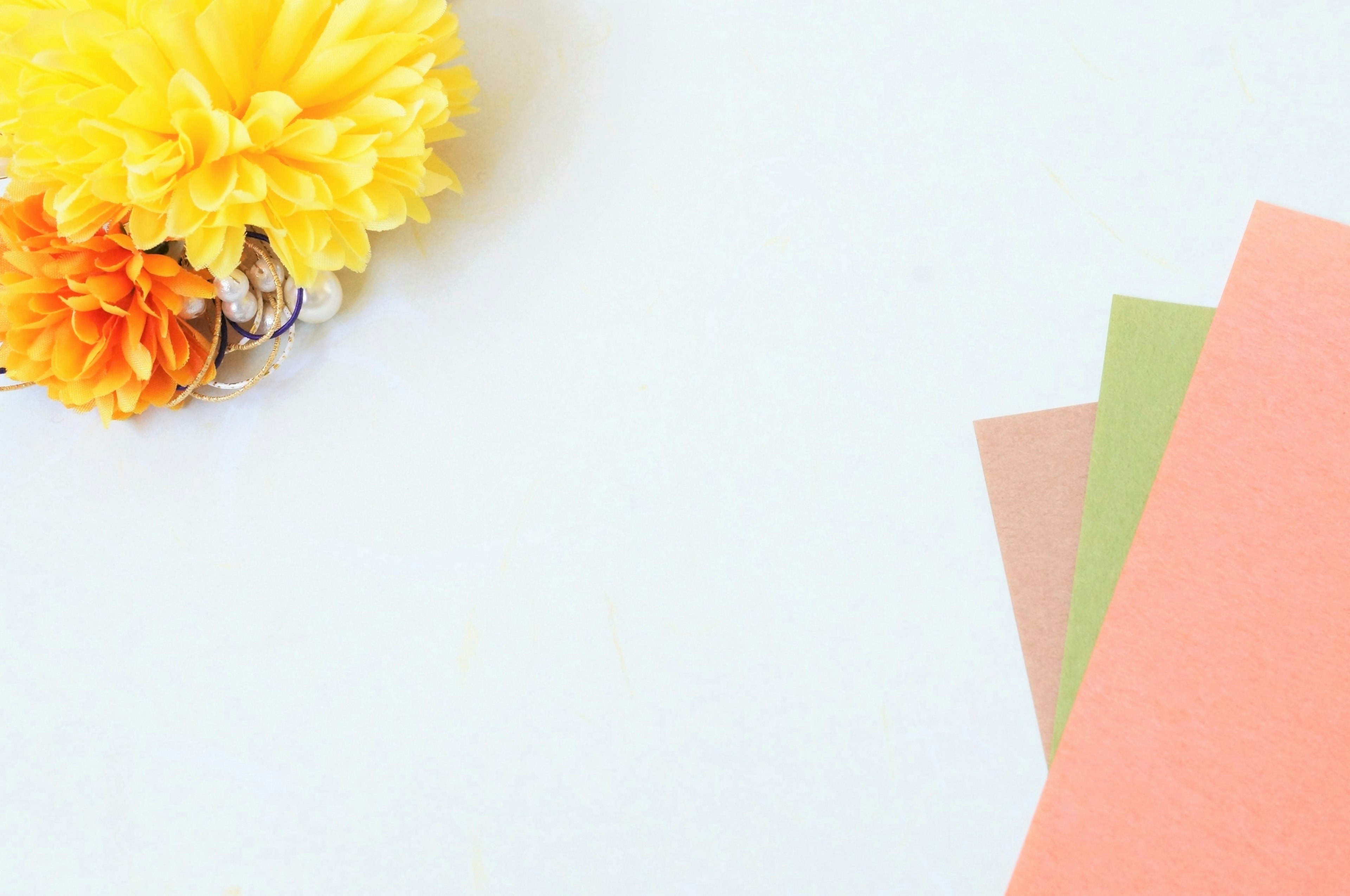 A vibrant yellow flower next to colorful paper sheets on a light background