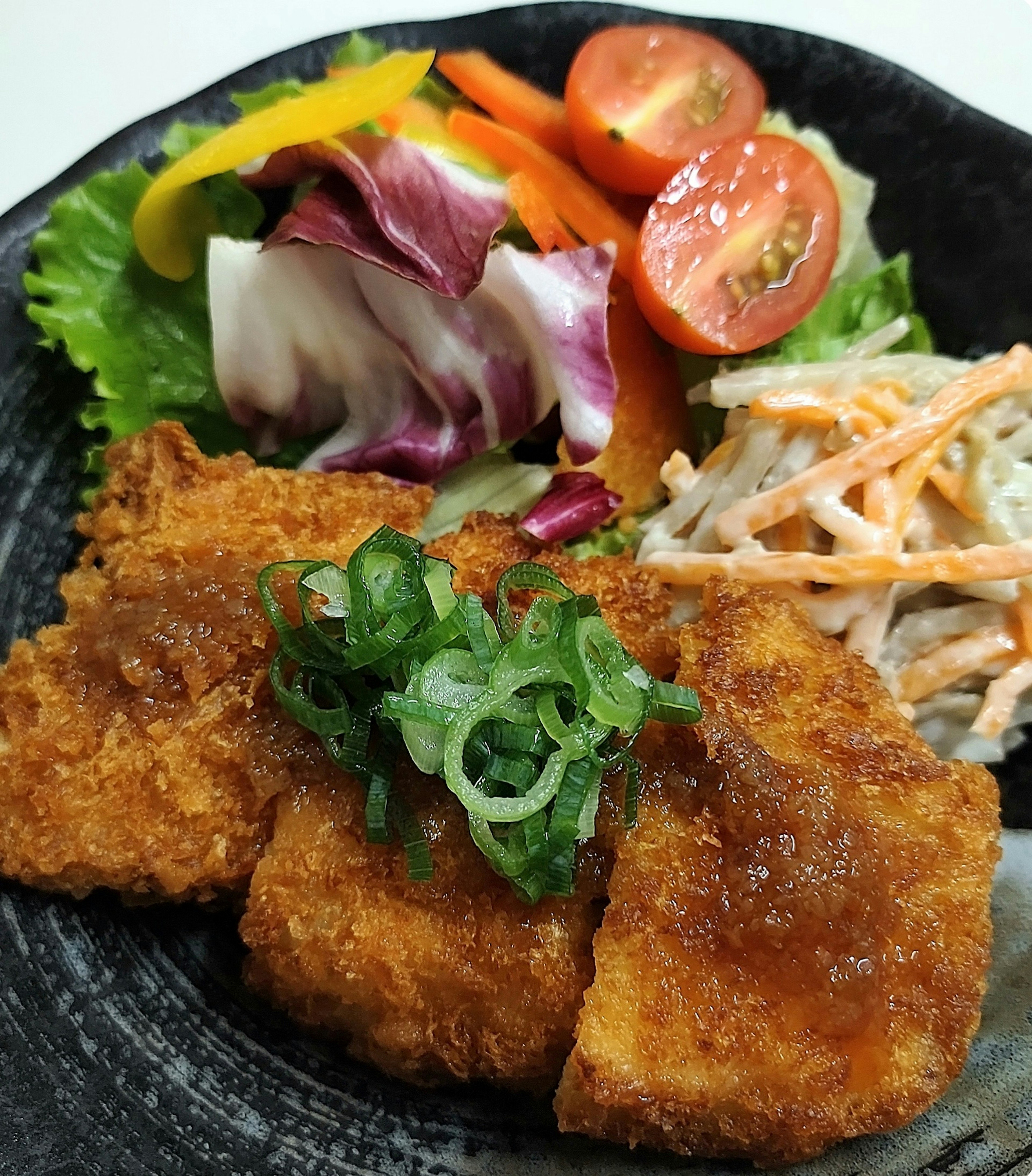 Potongan ayam goreng disajikan dengan salad segar dan sayuran