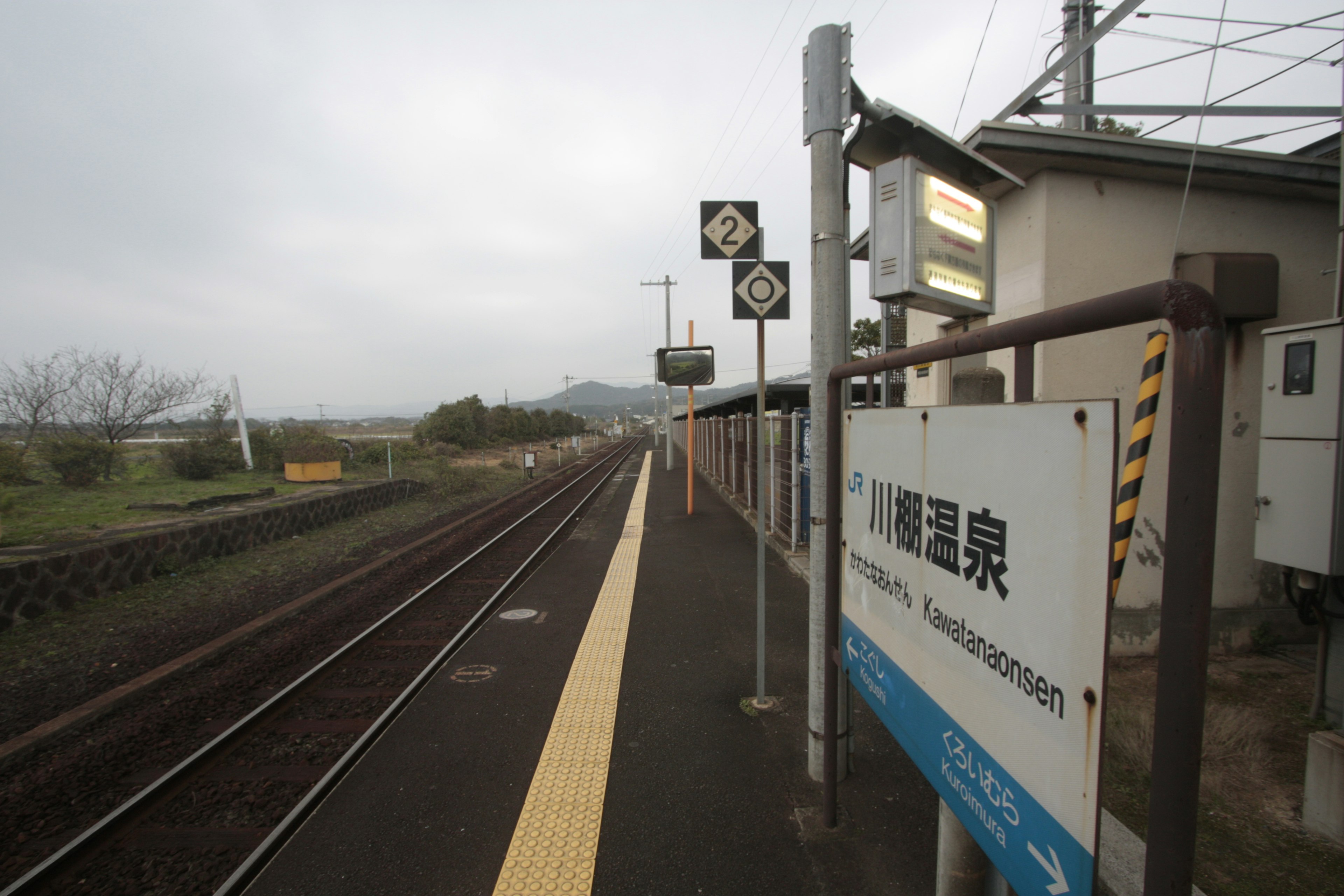 View of a train station platform and tracks under a cloudy sky