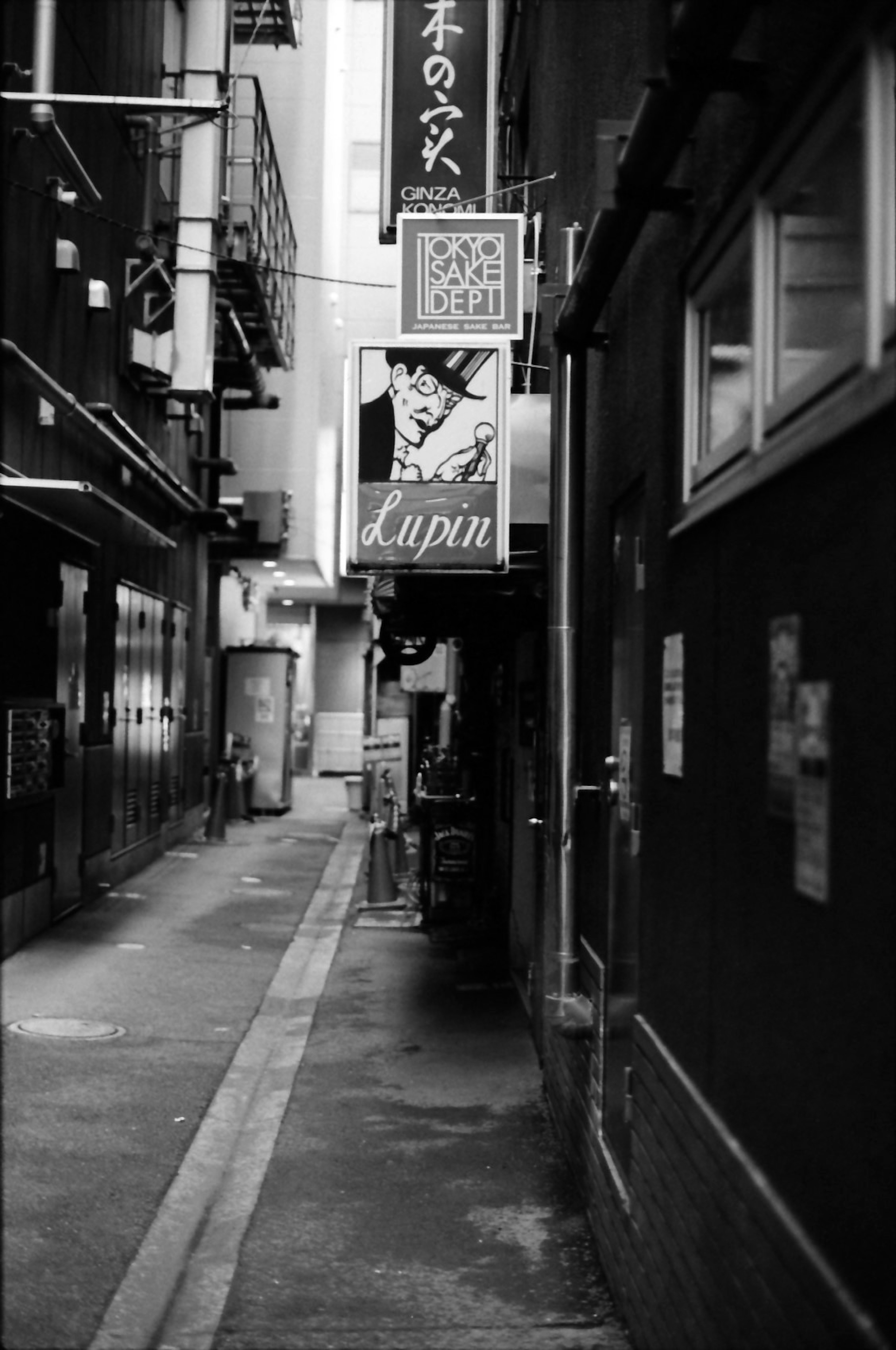 Schmale Gasse in Schwarzweiß mit einem japanischen Schild und Gebäuden