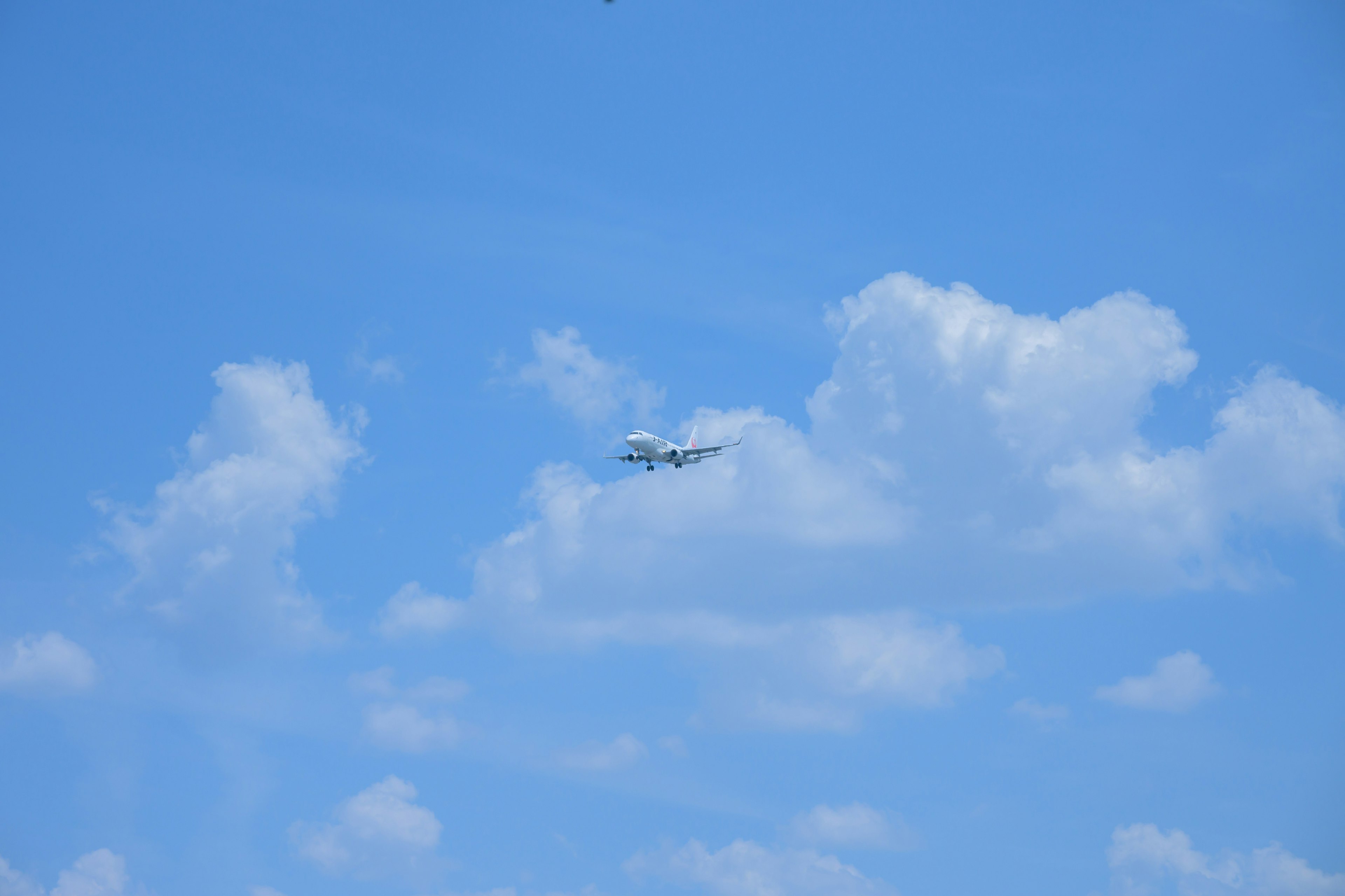 Avión volando en un cielo azul con nubes blancas